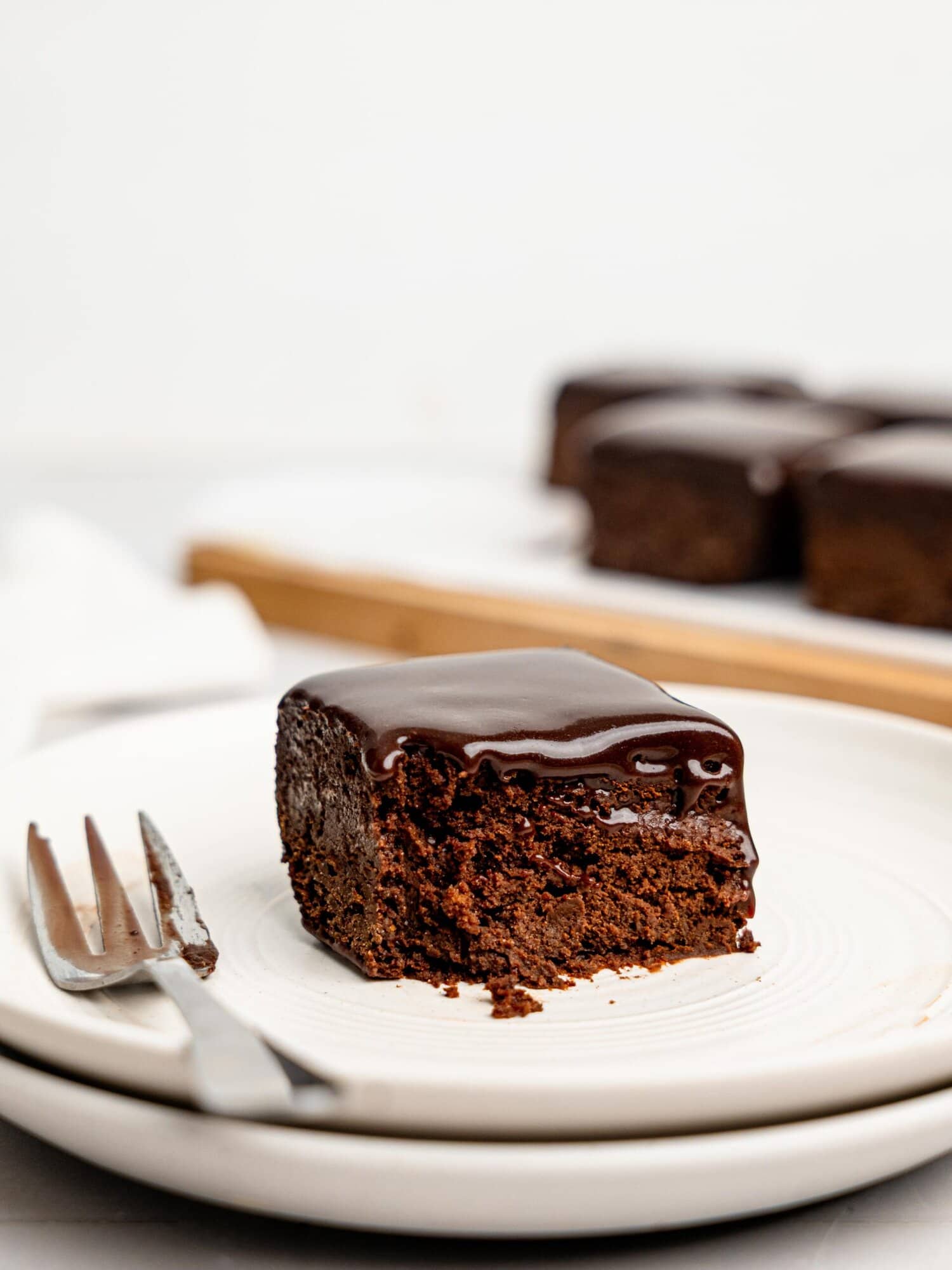A half-eaten chocolate ganache brownie on a white plate.