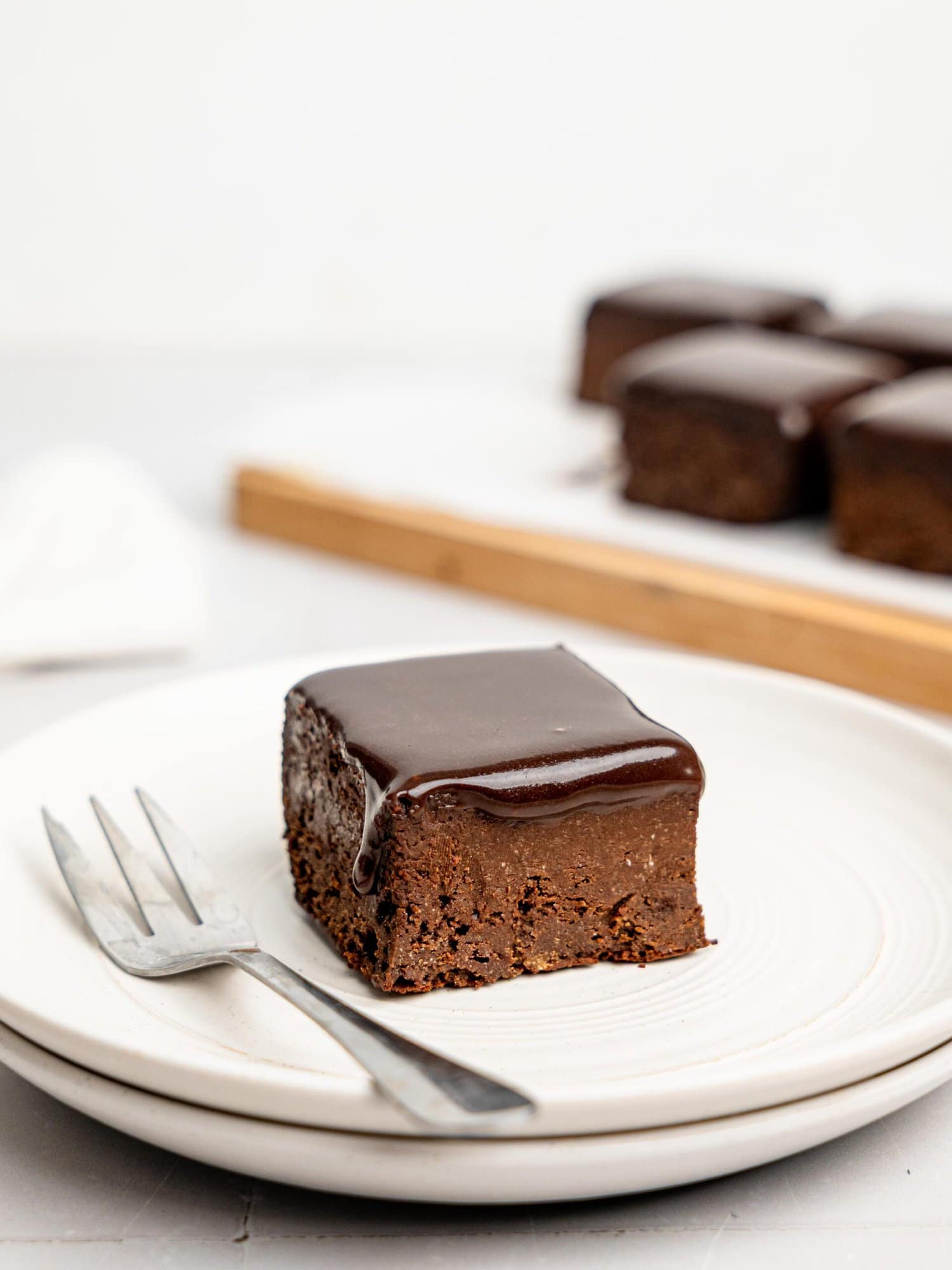 A chocolate ganache brownie on a white plate.