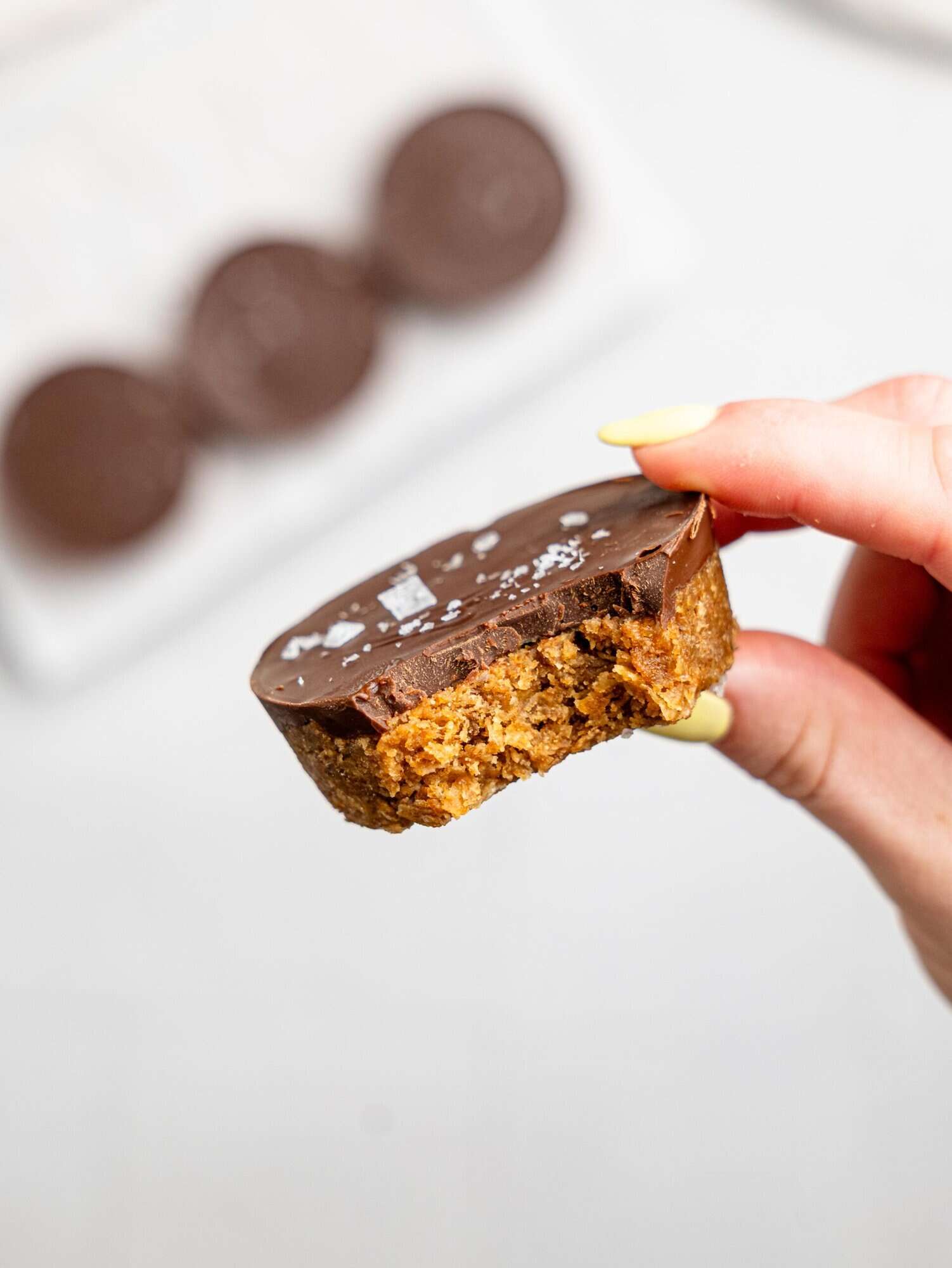 A hand holding a half-eaten peanut butter weetbix cup.