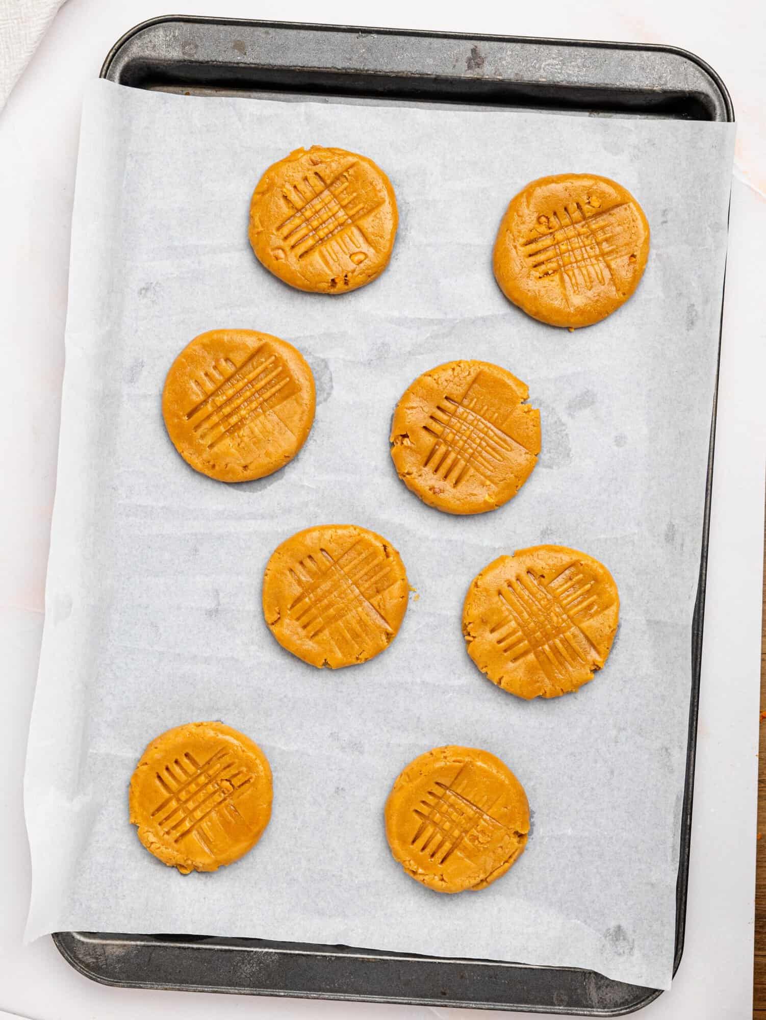 Peanut butter cookies on a baking tray before baking.