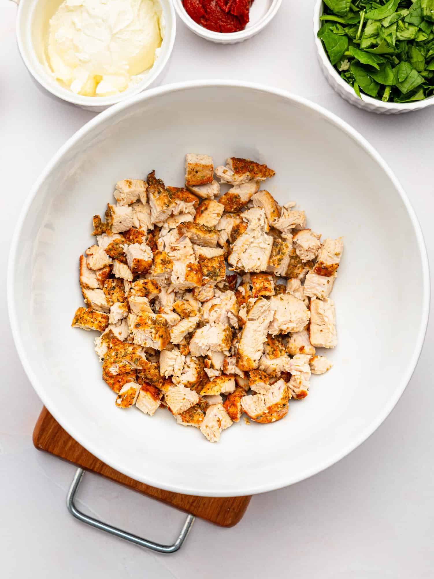 Chopped chicken breast in a white mixing bowl.