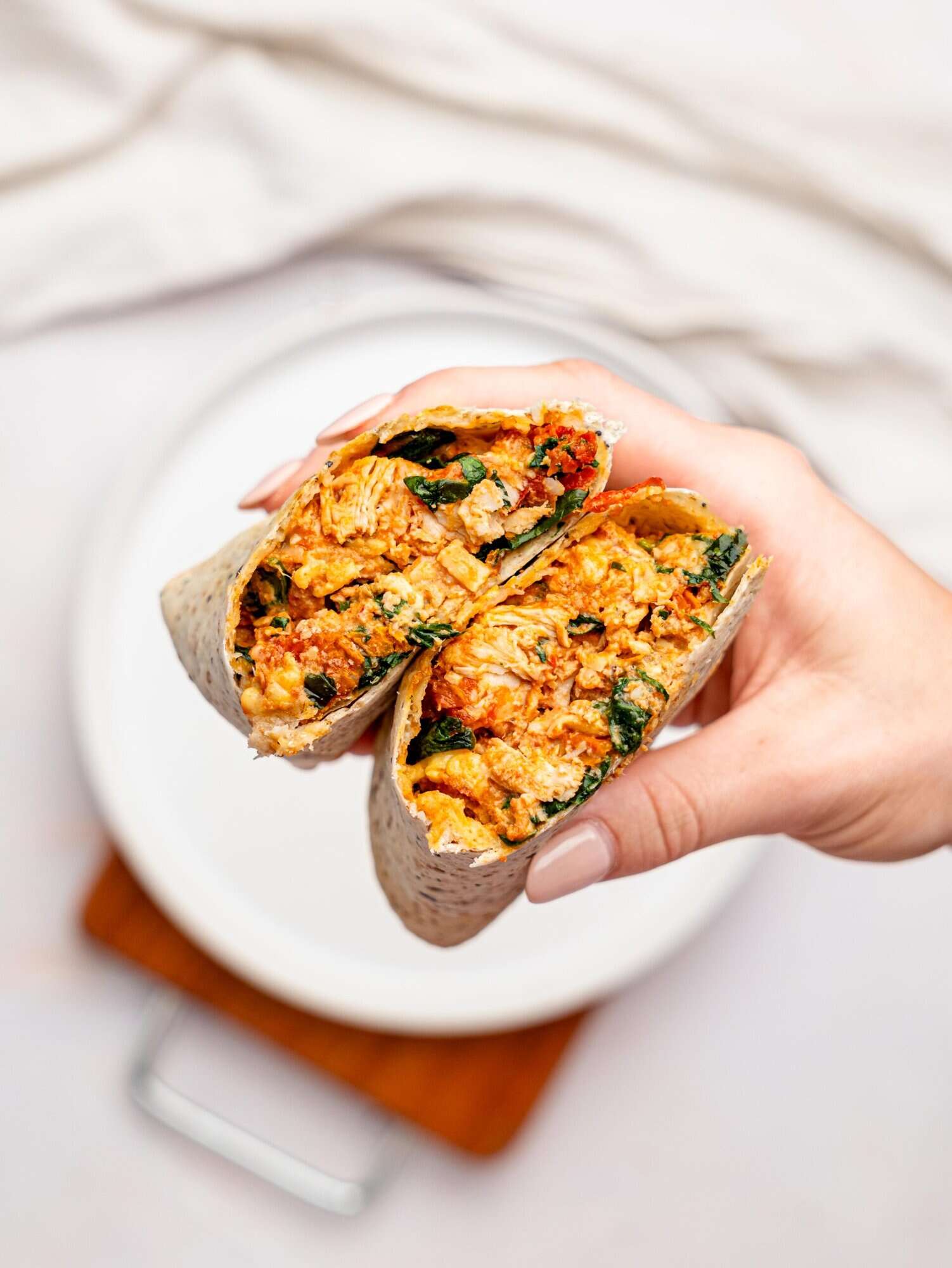 A hand holding a marry me chicken wrap.