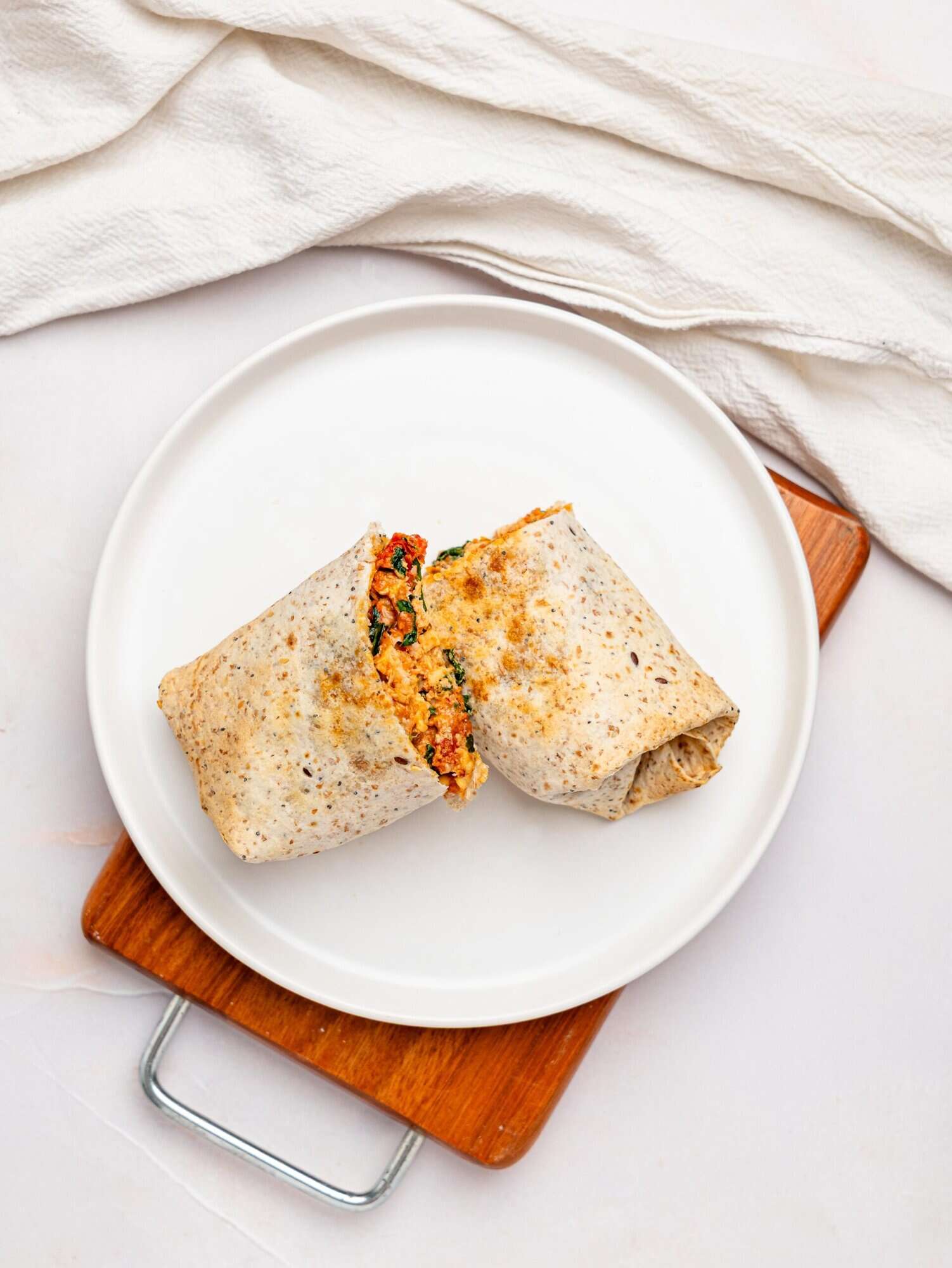 Marry me chicken wrap on a plate, sliced in half.