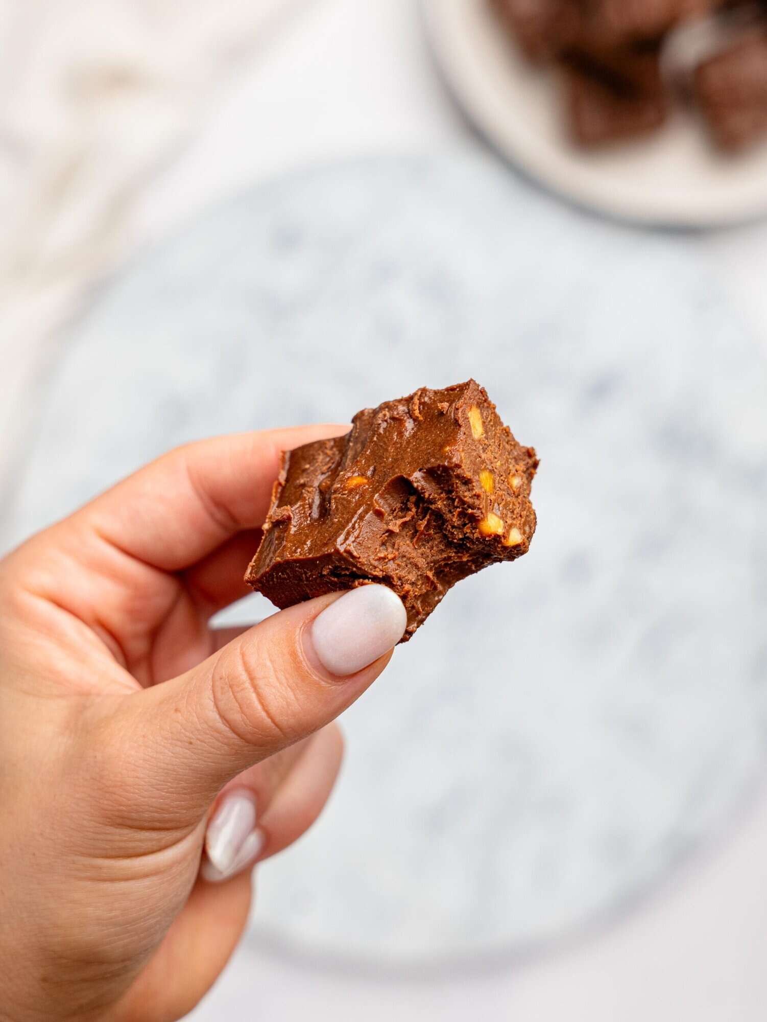A hand holding a half-eaten piece of healthier chocolate fudge.