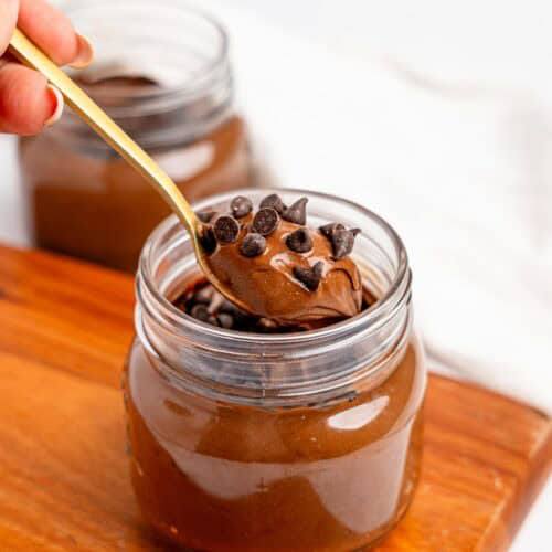 Hands taking a bite of mocha mousse from a glass jar.