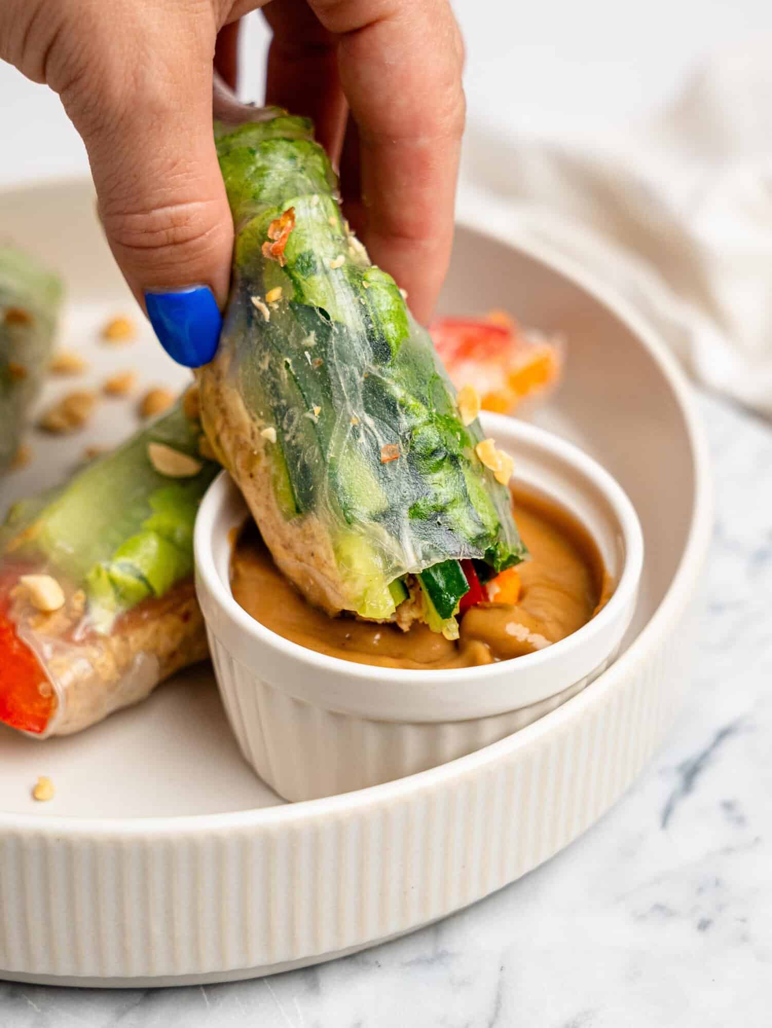 Dipping a Chicken Rice Paper Roll in peanut dipping sauce.