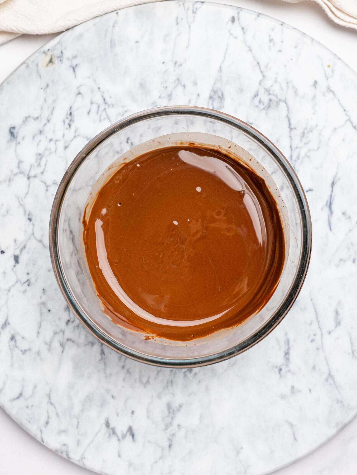 Melted dark chocolate in a glass bowl.