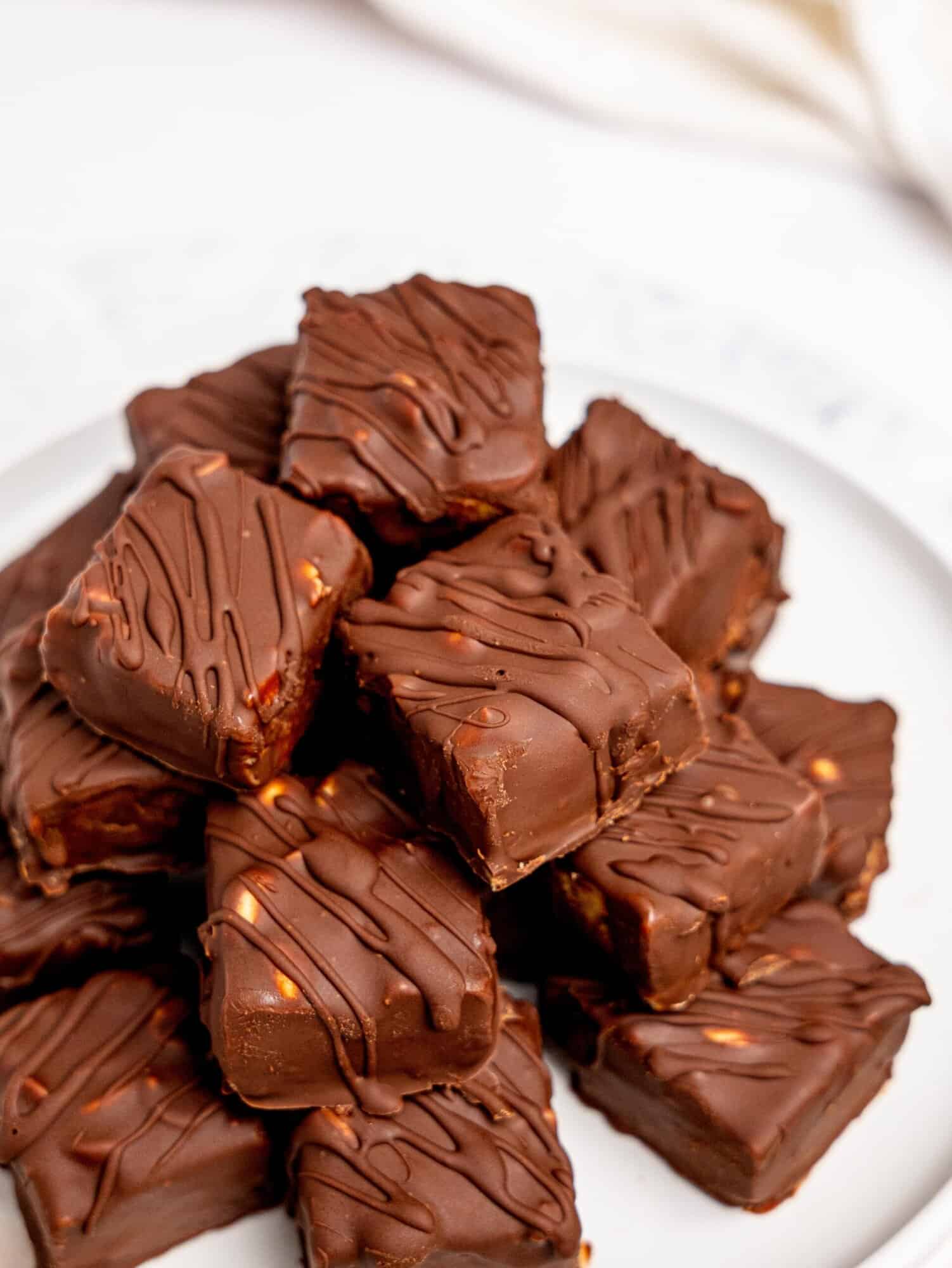 Healthy Snickers Bites stacked on a white plate.