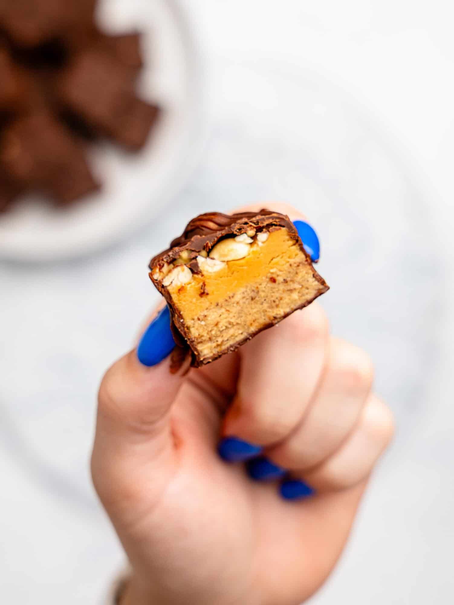 A hand holding a protein snickers bar.
