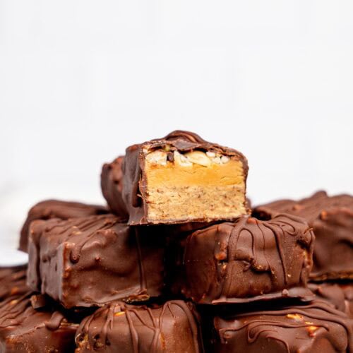 Protein Snickers Bites stacked on a white plate.