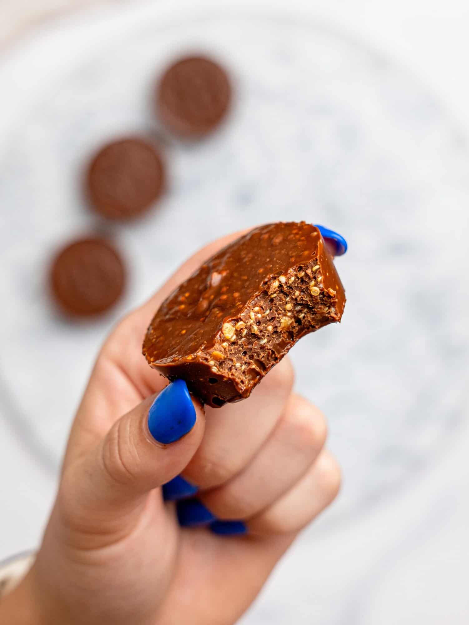 A hand holding a half-eaten quinoa crunch cup.