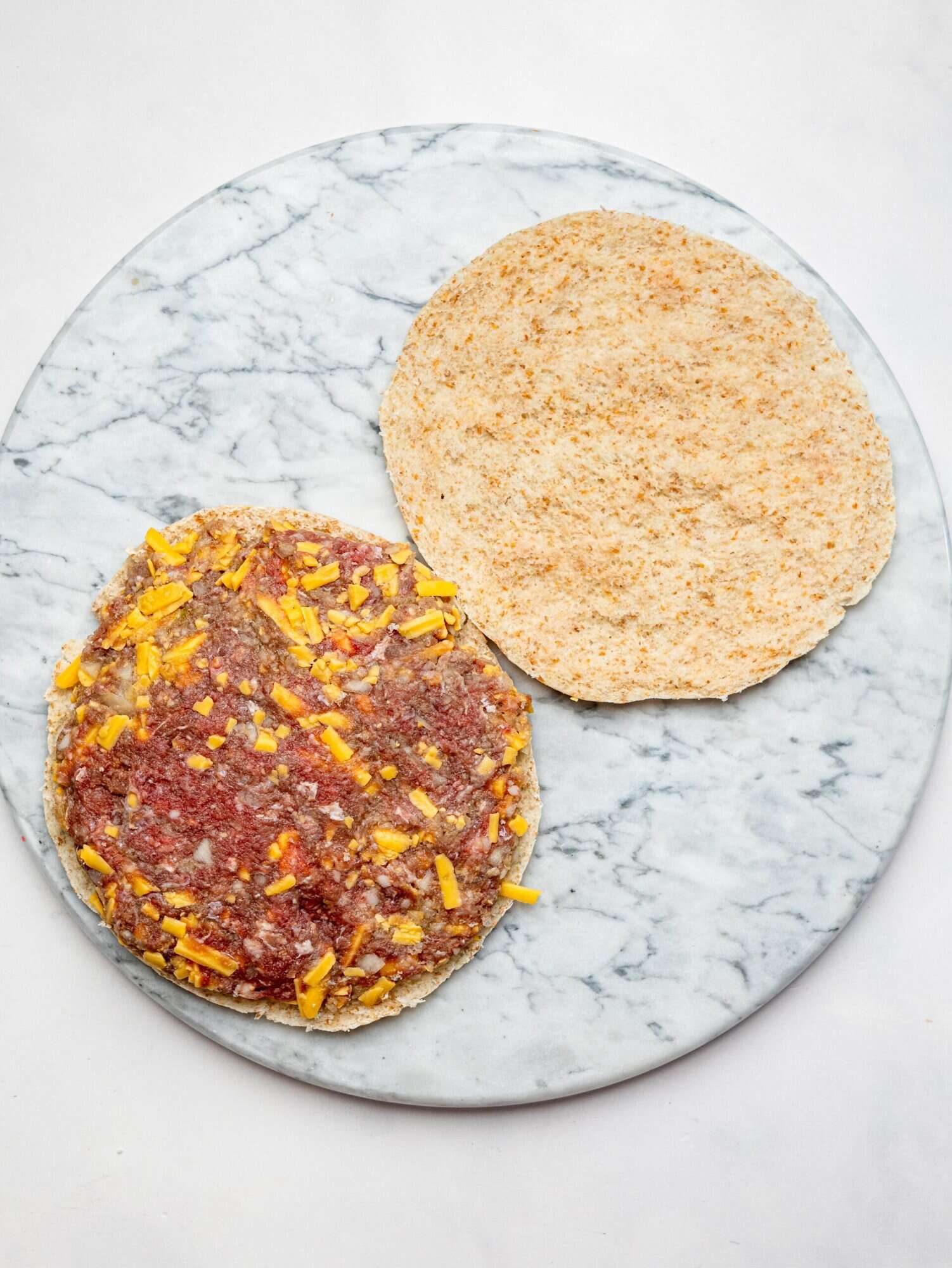 The cheesburger patty mixture pressed onto a pita.