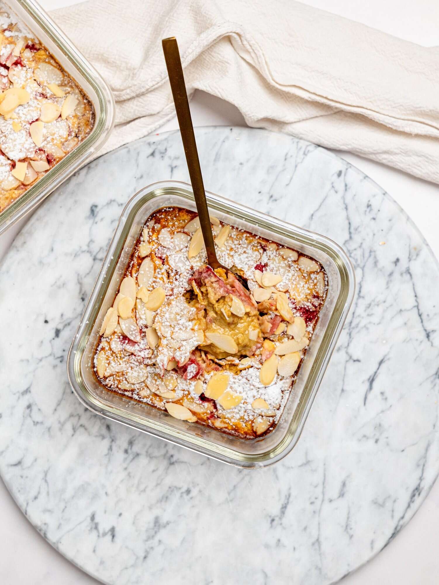 Gooey raspberry and almond protein baked oats in a glass meal-prep container.