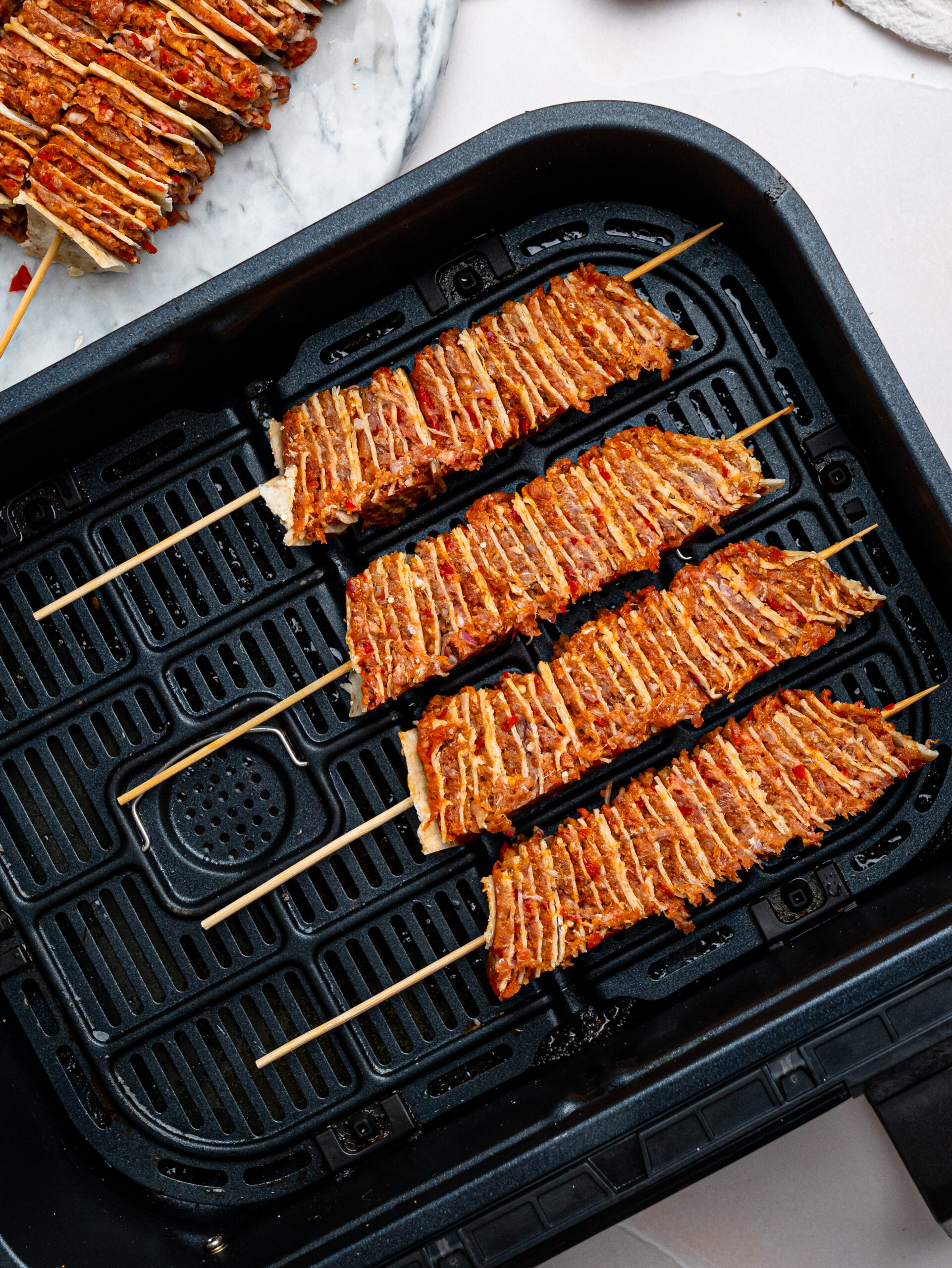 Four tortilla kebab skewers in a air fryer before cooking.