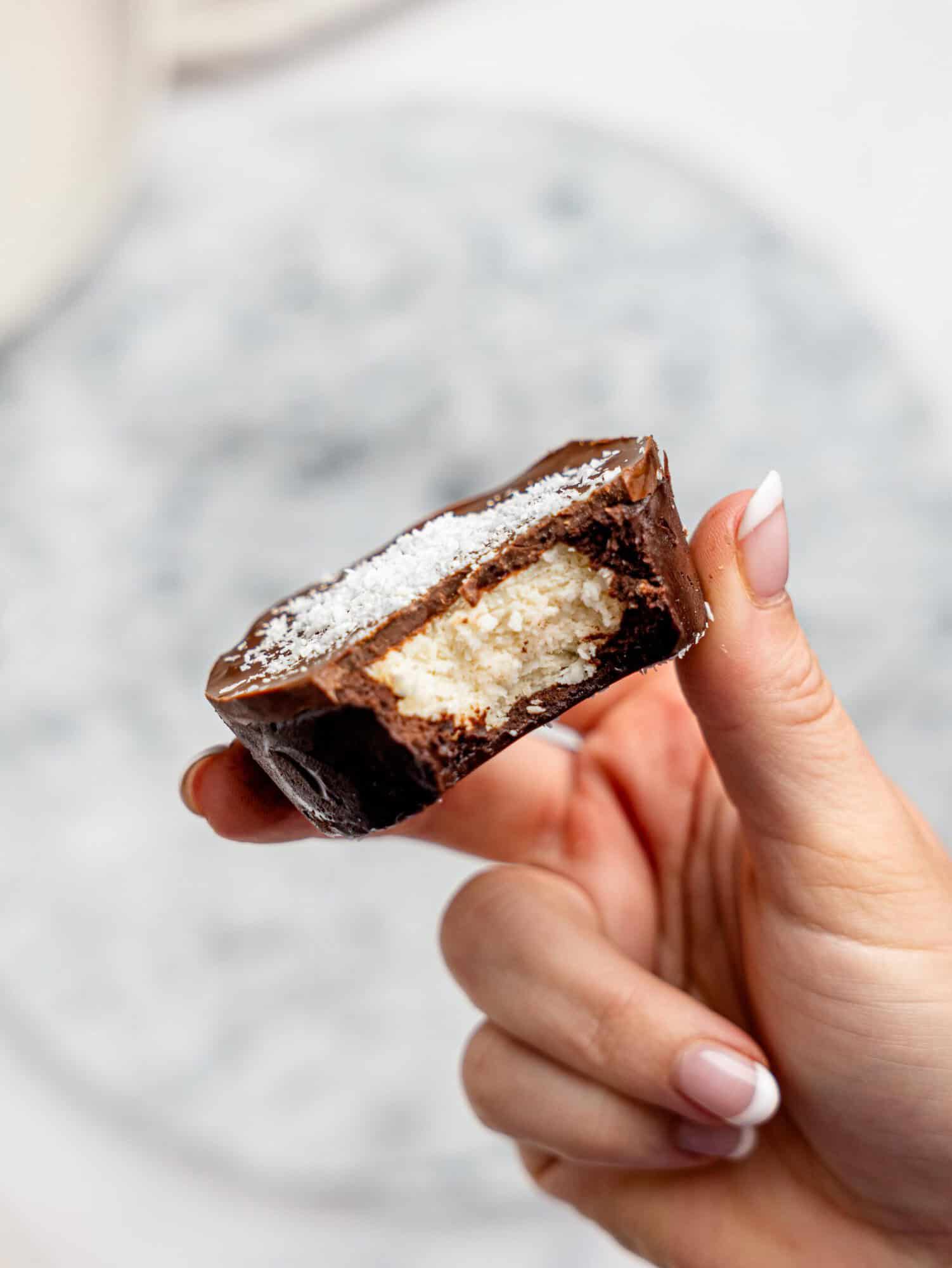 A hand holding a half-eaten bounty brownie cup.