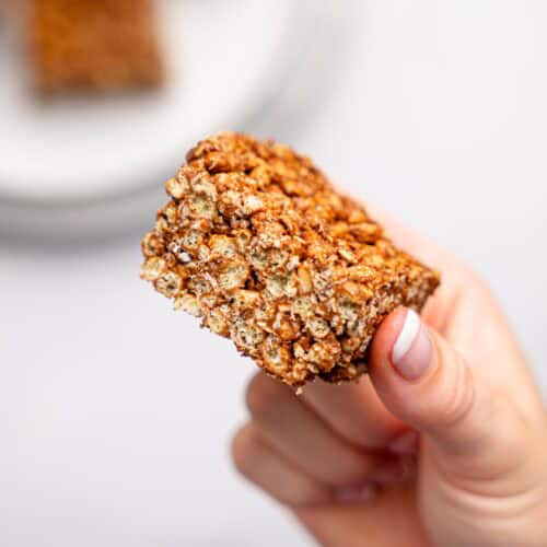 A hand holding a peanut butter rice krispie square.