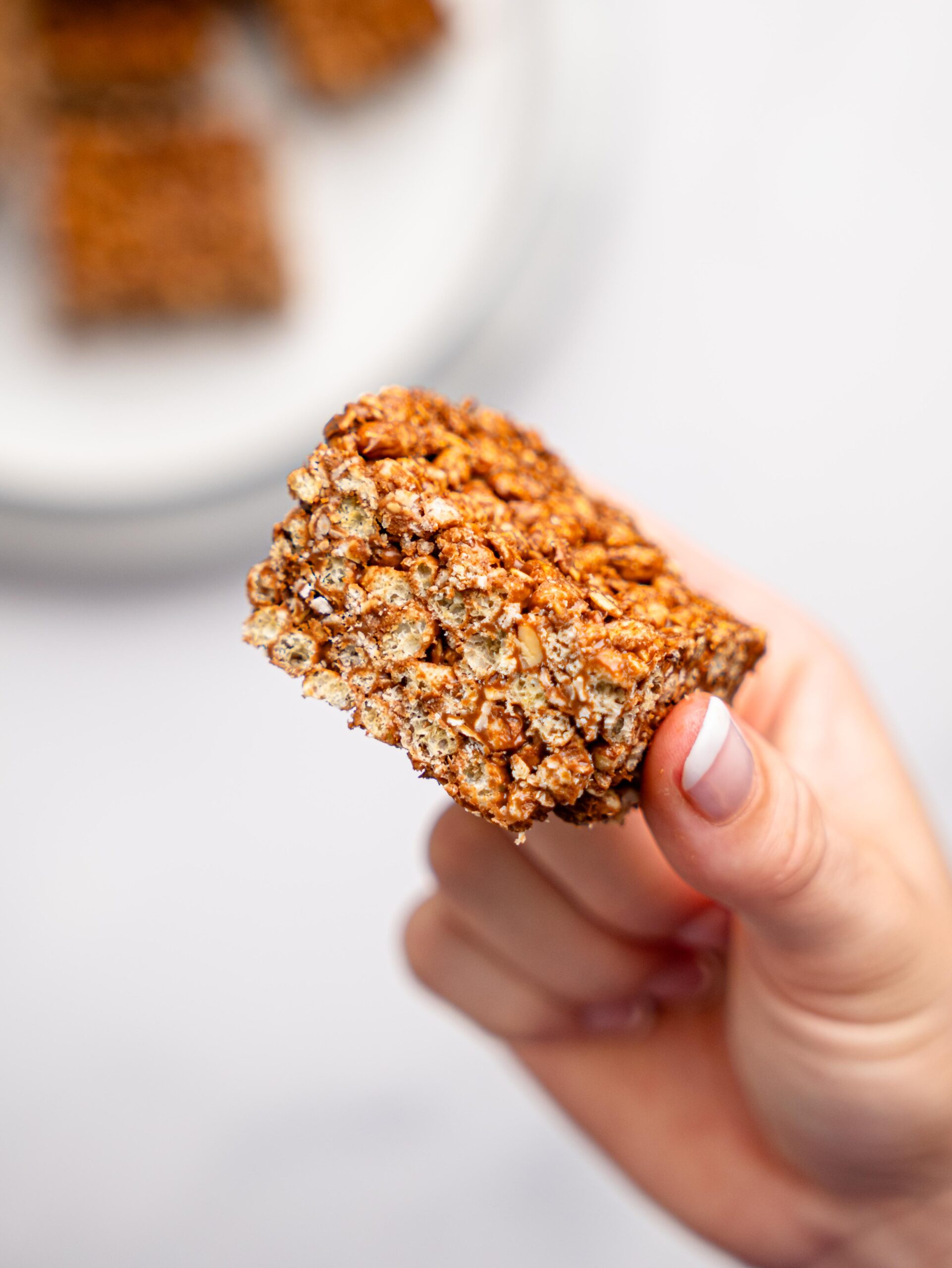 A hand holding a peanut butter rice krispie square.