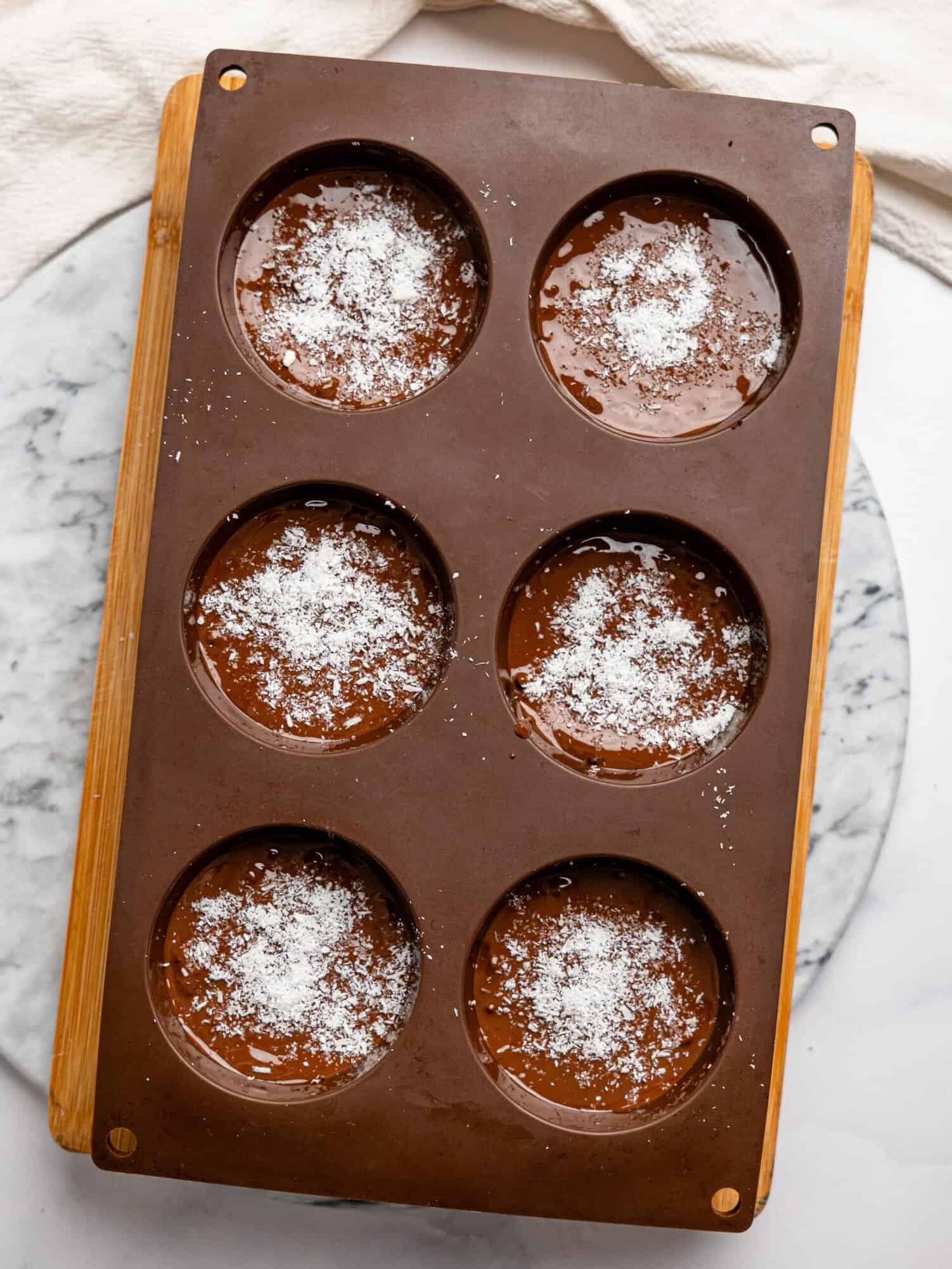 Bounty brownie cups in a brown silicone muffin tray before setting in the fridge.