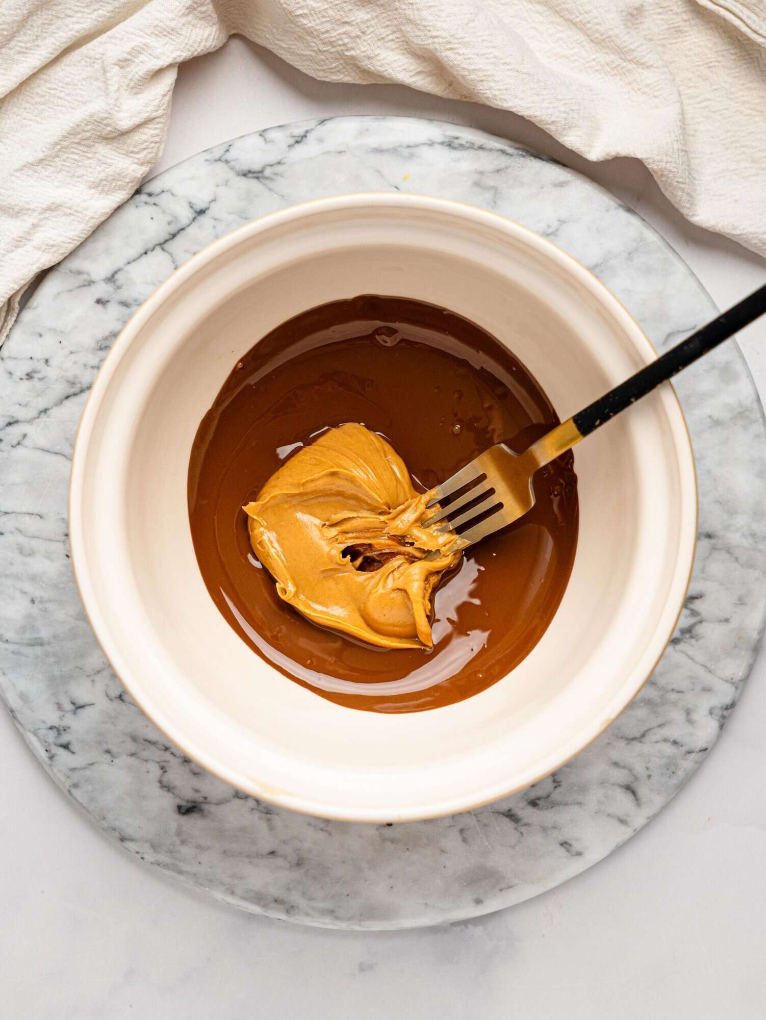 Melted dark chocolate and peanut butter in a white mixing bowl.