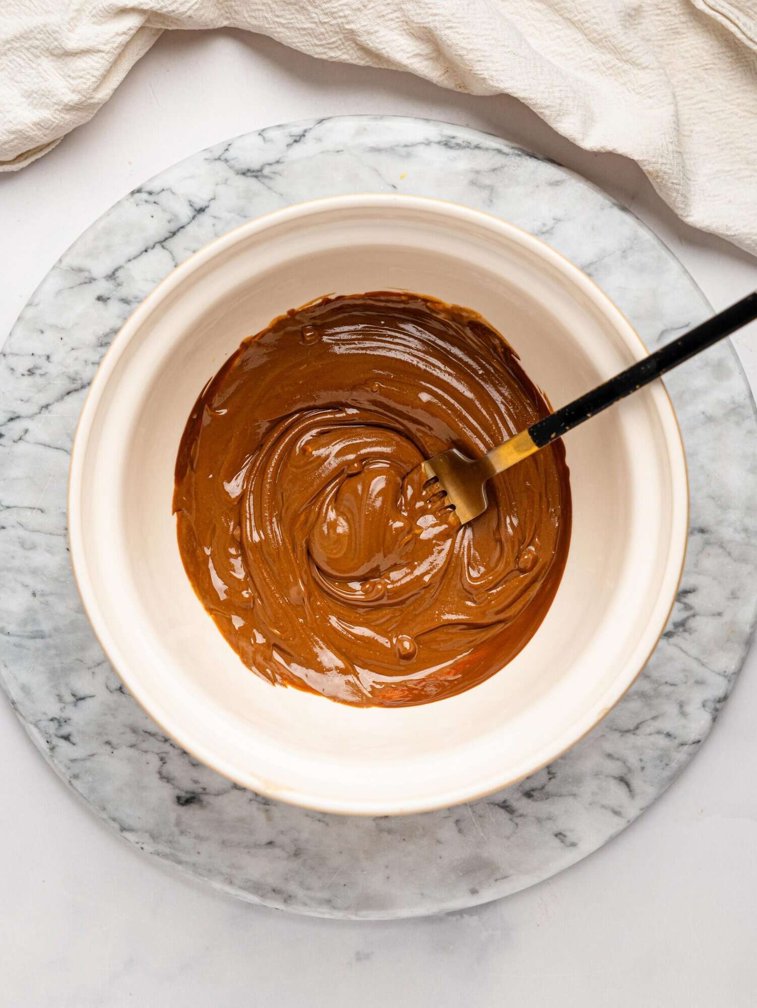 Melted dark chocolate and peanut butter combined in a white mixing bowl.