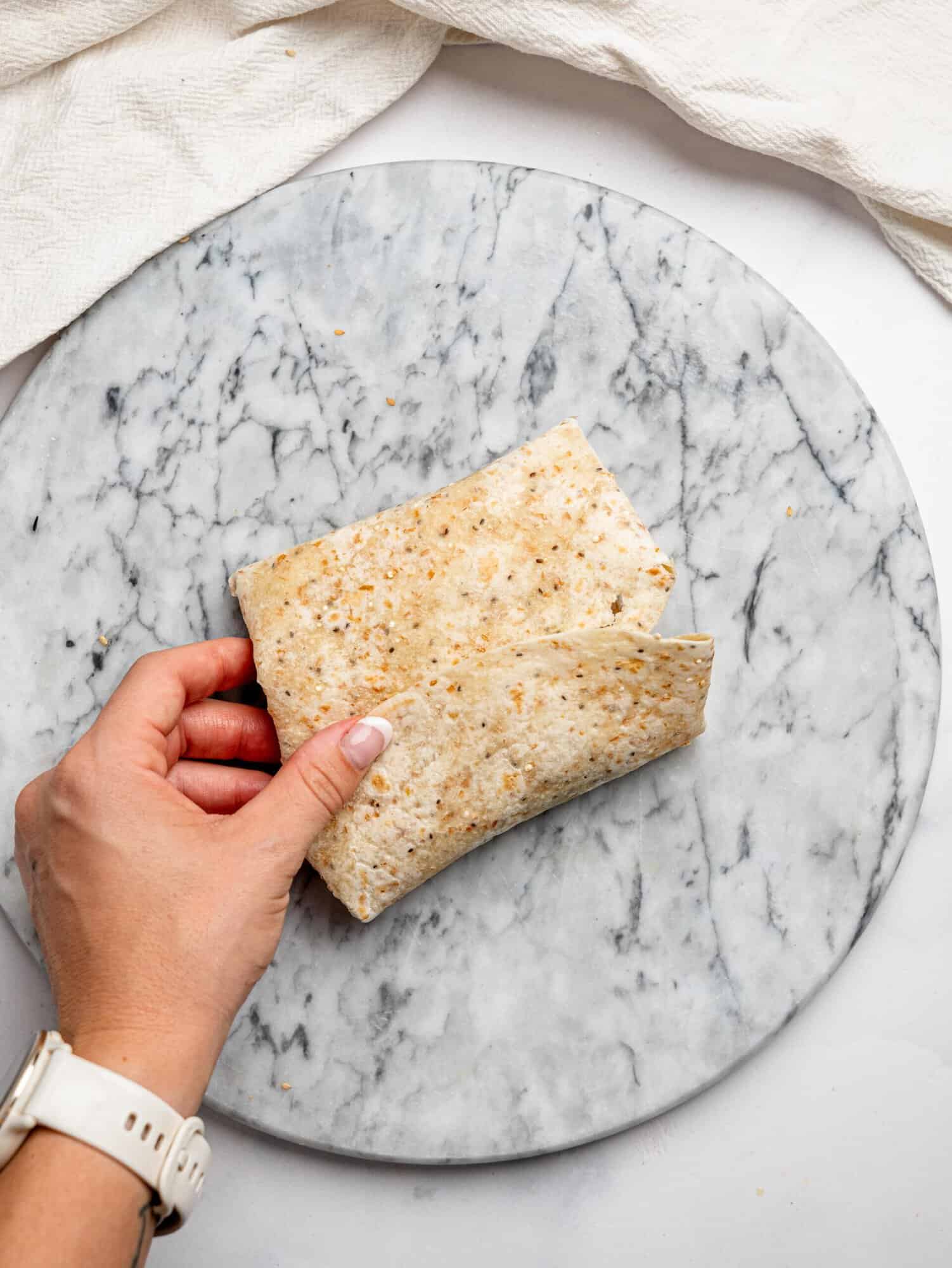 A tortilla folded over into a sealed wrap shape, held by hand, showing how the egg wrap is formed.