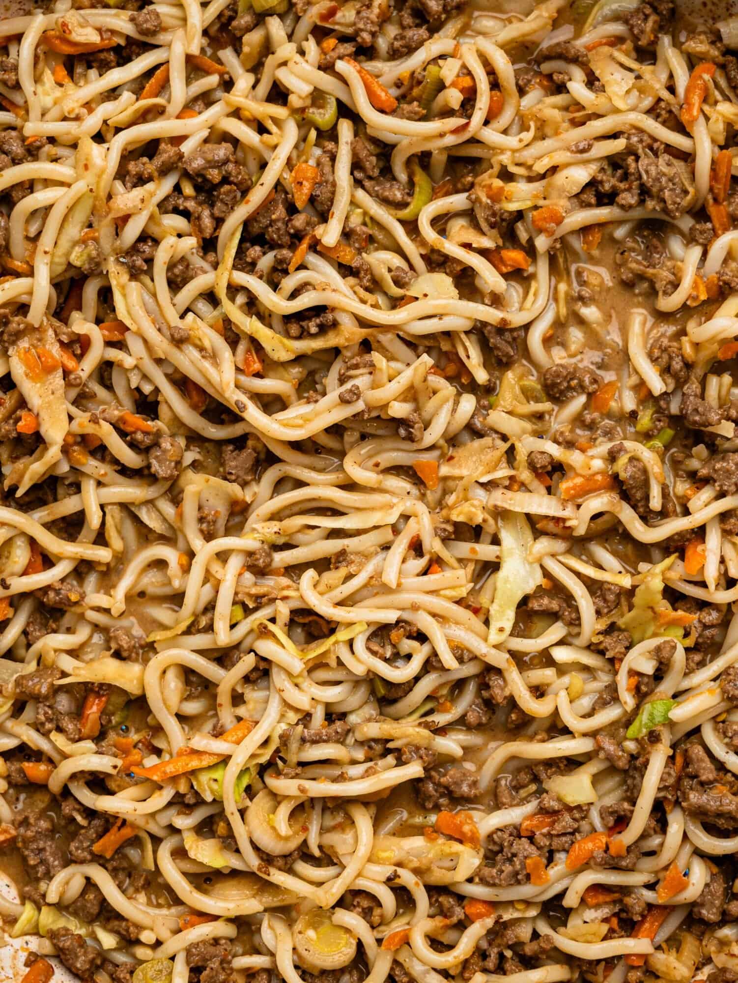 Spicy peanut butter noodles, ground beef, and vegetables close-up.