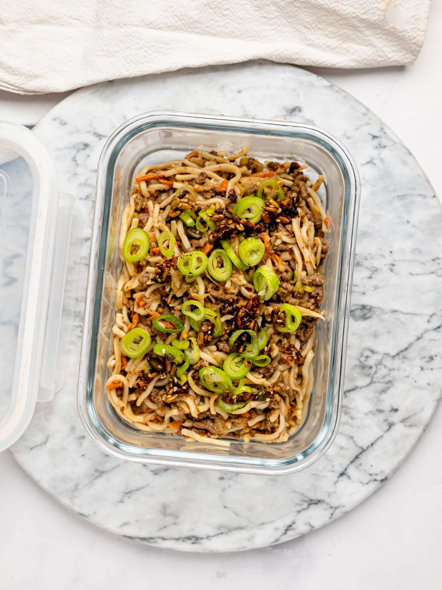 Spicy peanut butter noodles, ground beef, and vegetables in a meal-prep container.