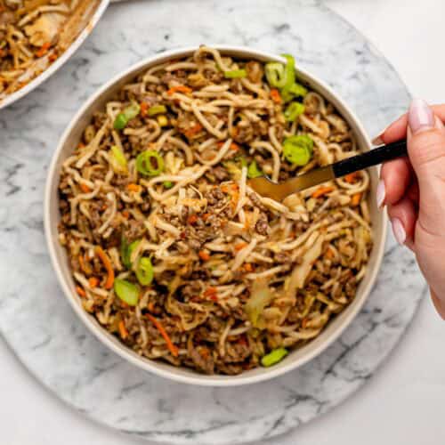 Spicy peanut butter noodles, ground beef, and vegetables in a white bowl.