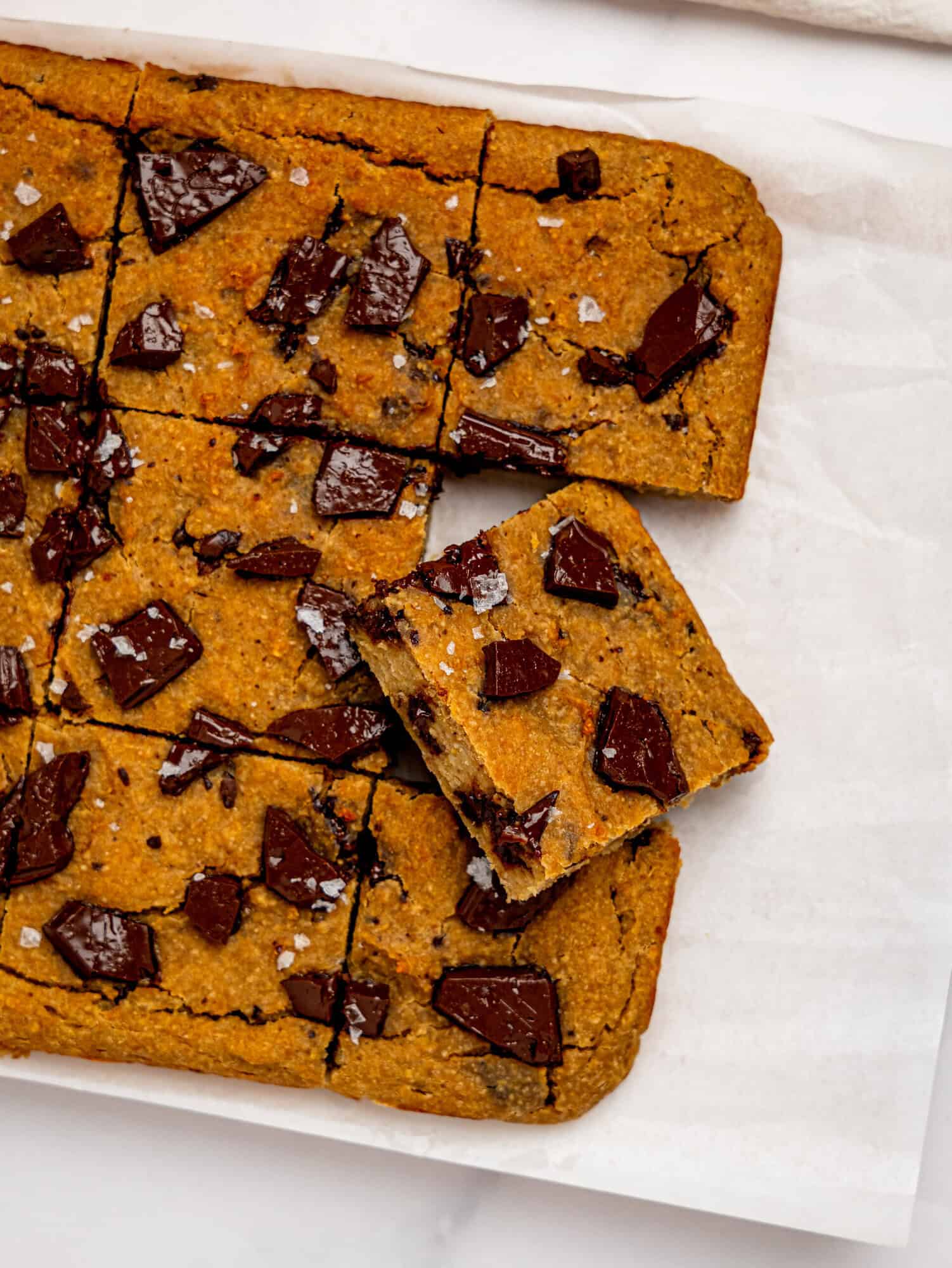 Bird's eye view of chickpea cookie bars on a sheet of white parchment paper.