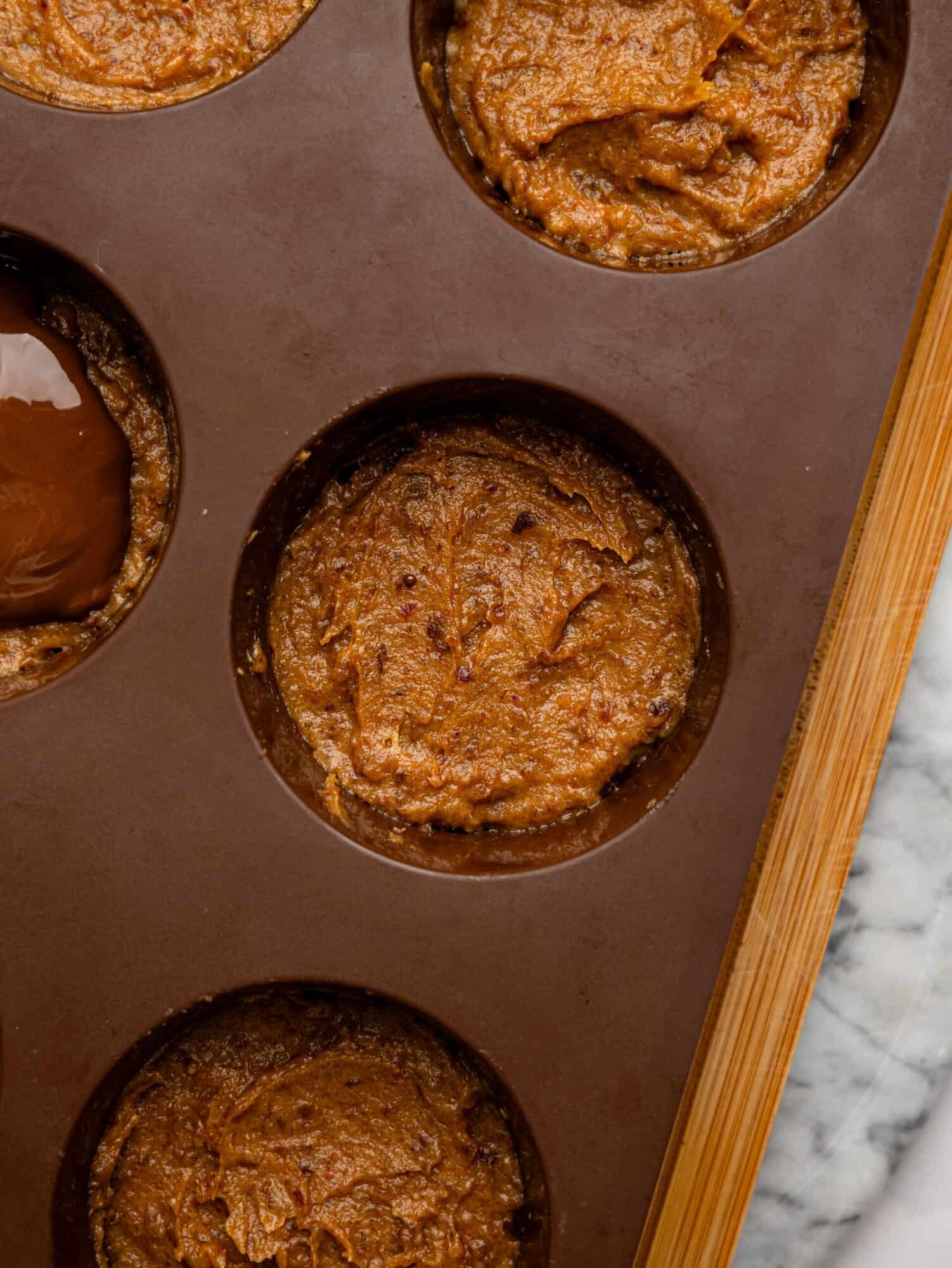 Millionaires' Weetbix Cups base in a brown silicone muffin tray topped with date caramel.