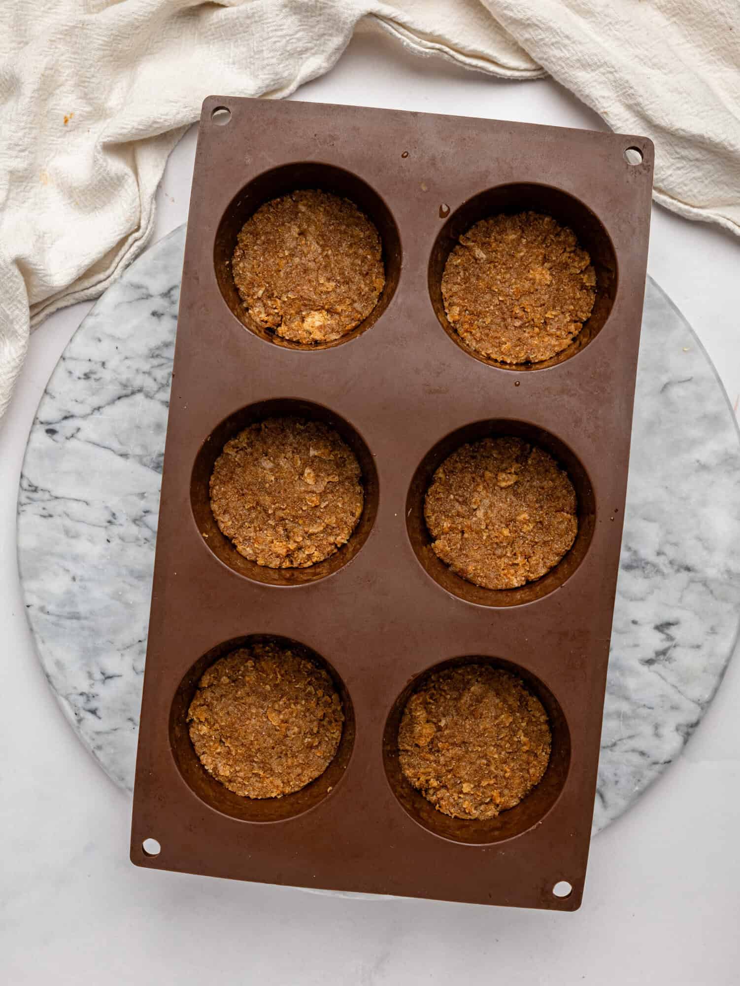 Weetbix Millionaires' Cups base pressed into a brown silicone muffin tray.