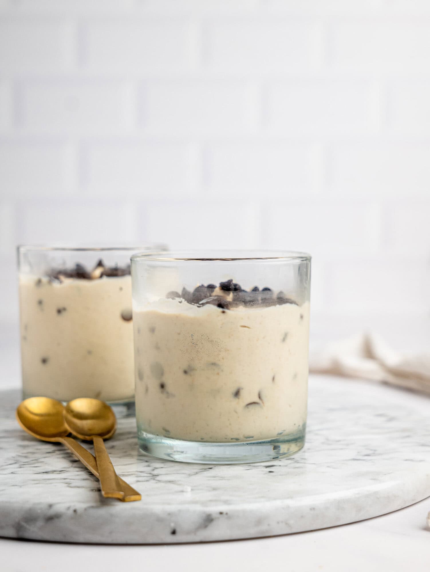 Side view of creamy Cottage Cheese Cookie Dough Mousse topped with dark chocolate chips in glass dessert cups.