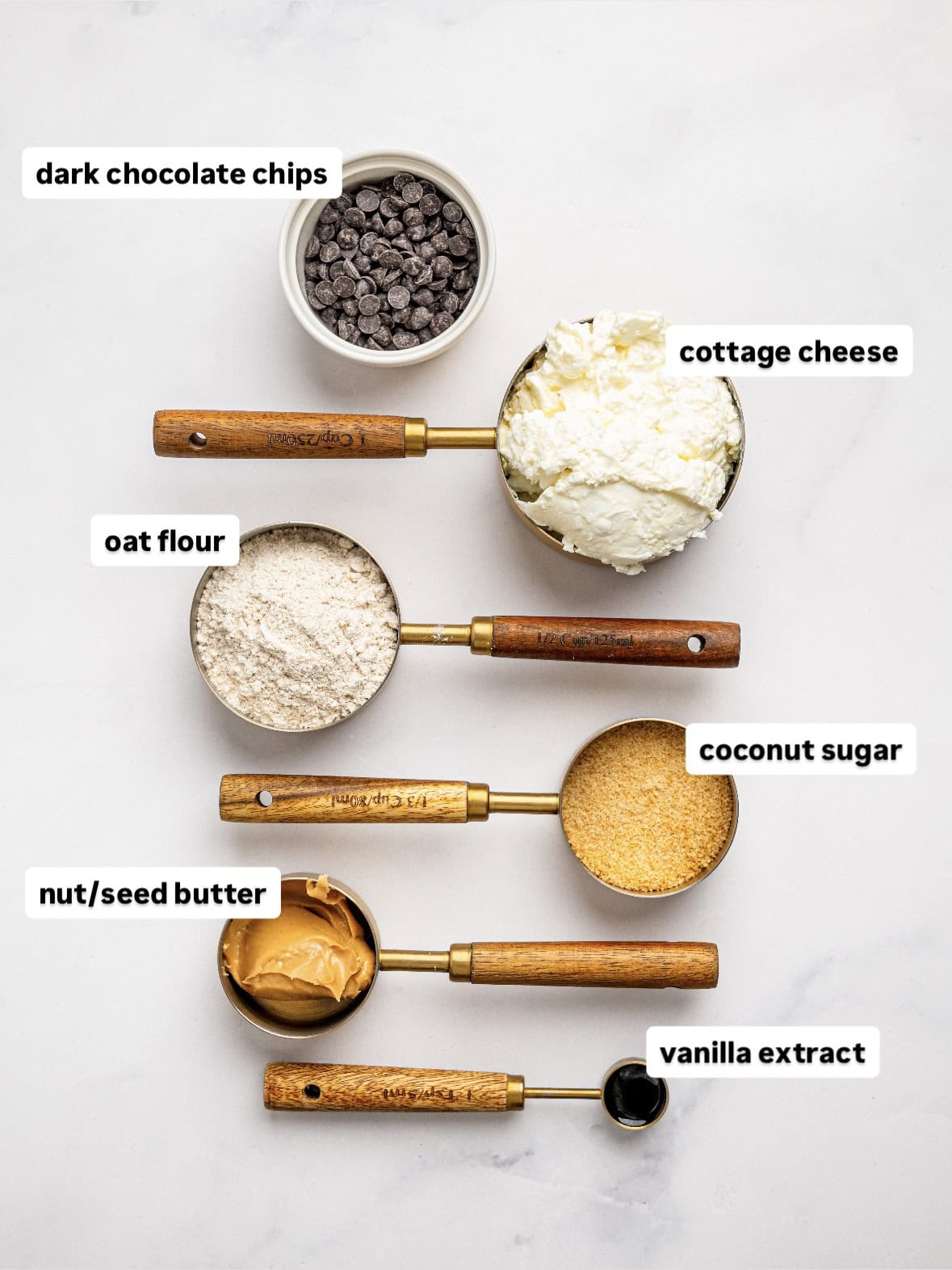 Ingredients needed to make Cottage Cheese Cookie Dough Mousse including cottage cheese, nut butter, oat flour, coconut sugar, vanilla extract, and dark chocolate chips.
