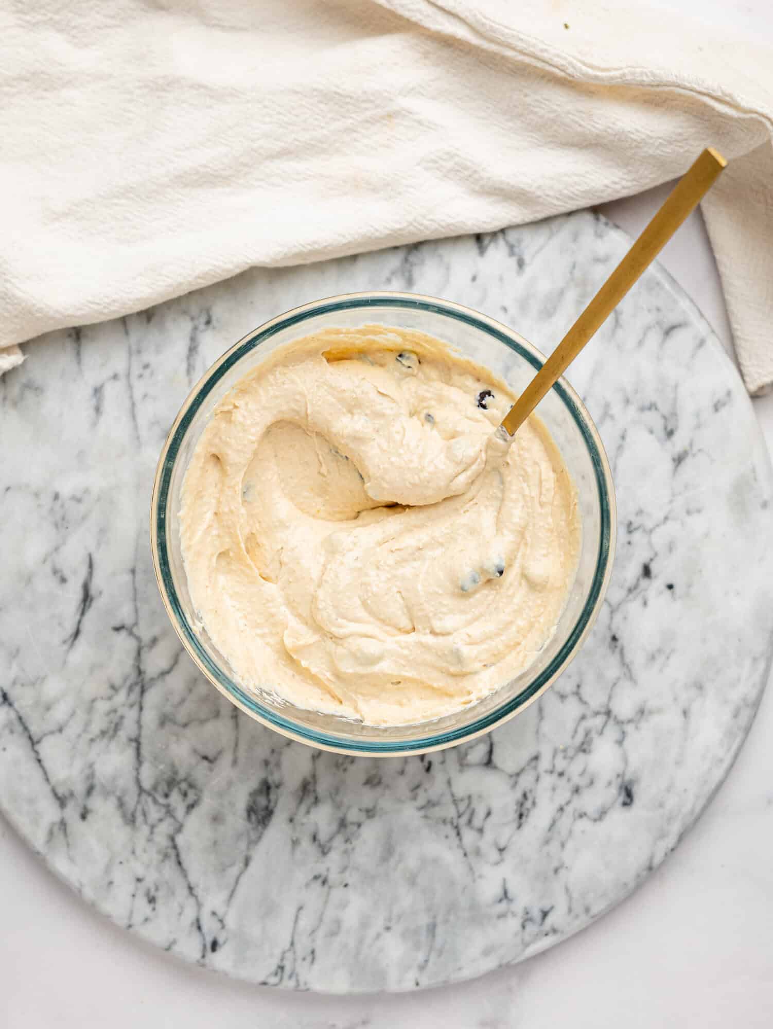 Overhead view of Cottage Cheese Cookie Dough Mousse topped with dark chocolate chips in a glass mixing bowl.