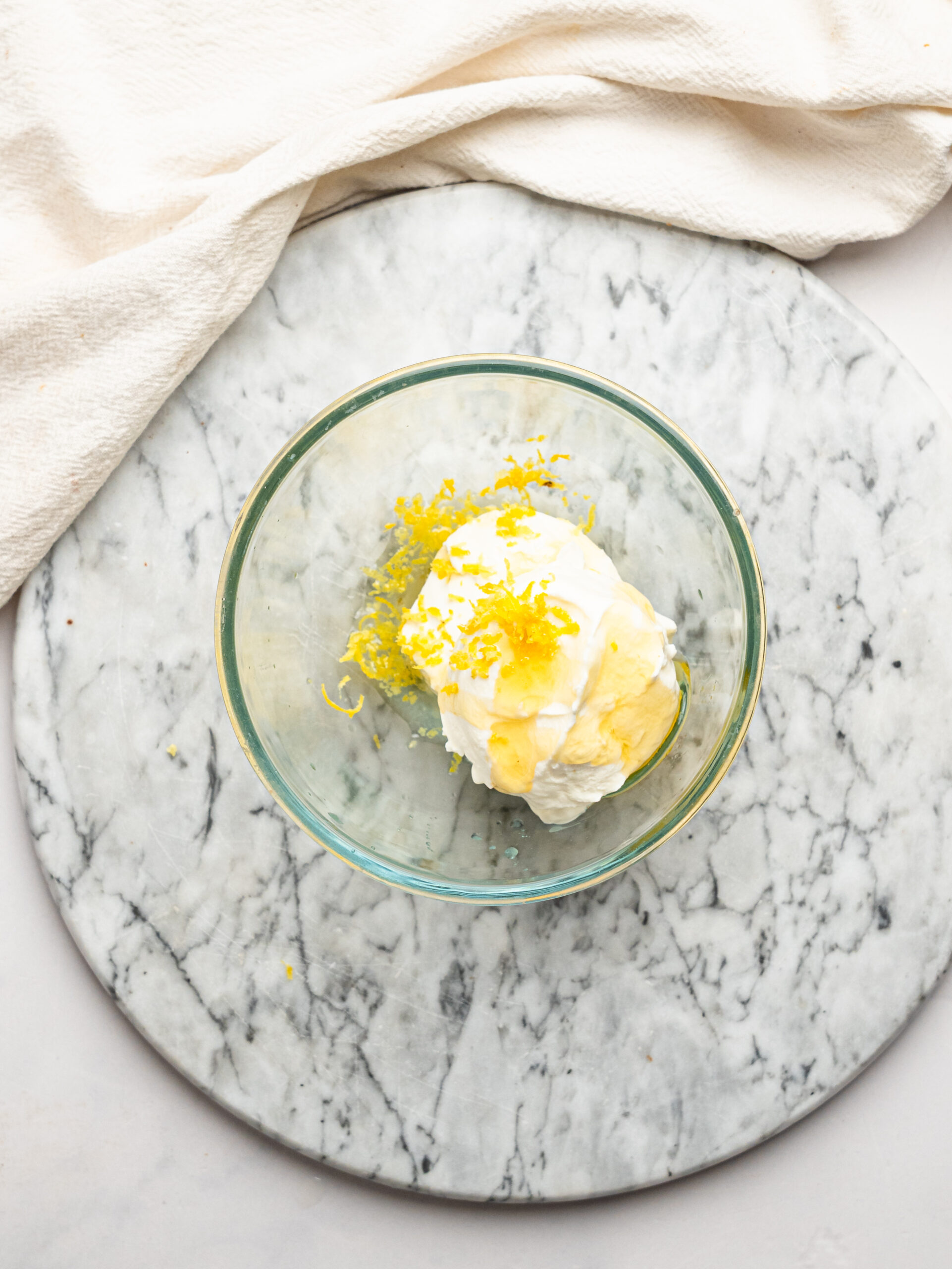 Cottage cheese, Greek yogurt, honey, lemon juice, and lemon zest added to a glass bowl to make the lemon cheesecake filling.