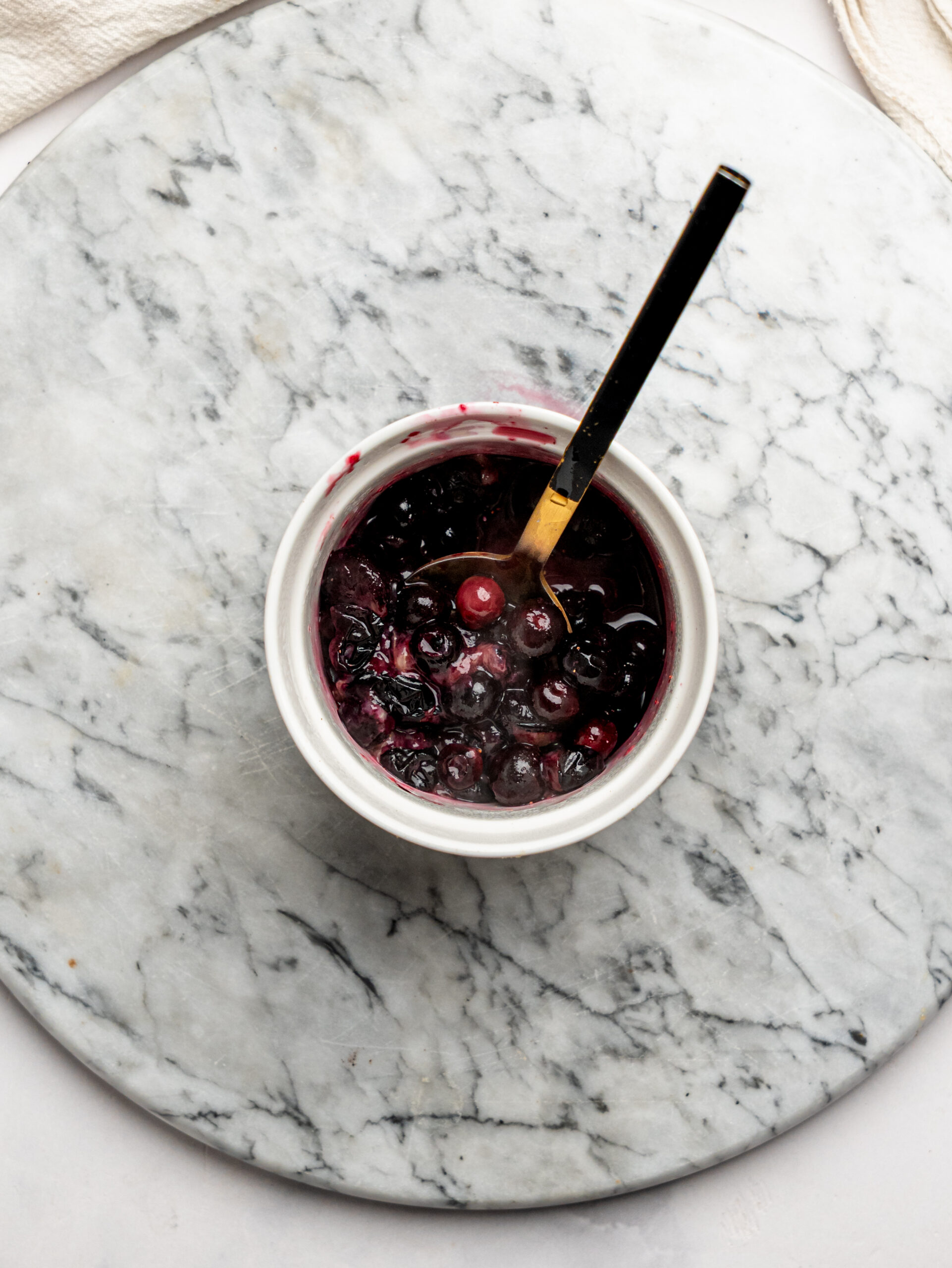 Homemade berry topping made from cooked frozen berries in a small bowl with a spoon.