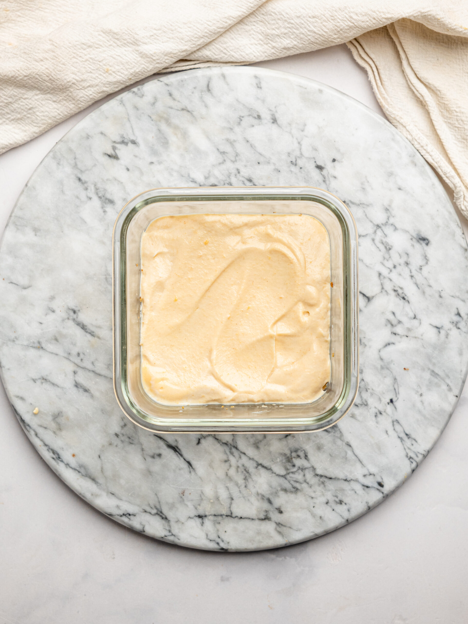 Smooth peanut butter yogurt mixture spread evenly over a softened Weetbix base in a glass container.
