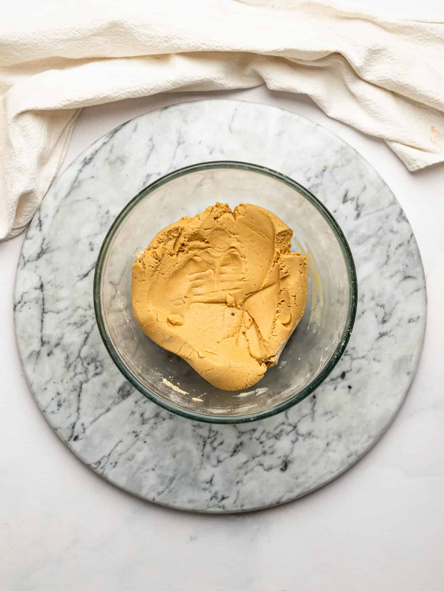 Thick peanut butter filling made with vanilla protein powder and sweetener mixed in a glass bowl, ready to be shaped into protein peanut butter cups.