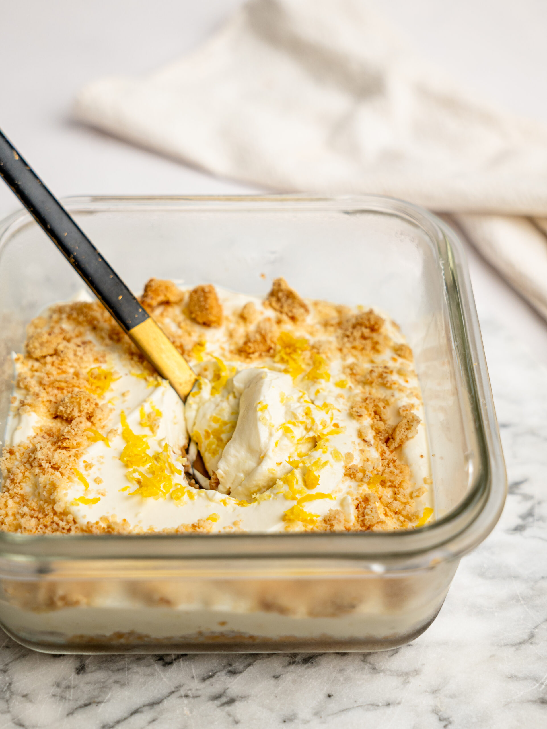 Side view of lemon cheesecake overnight Weet-Bix showing layers of Weet-Bix base and creamy lemon cheesecake filling, topped with biscuit crumbs and lemon zest.