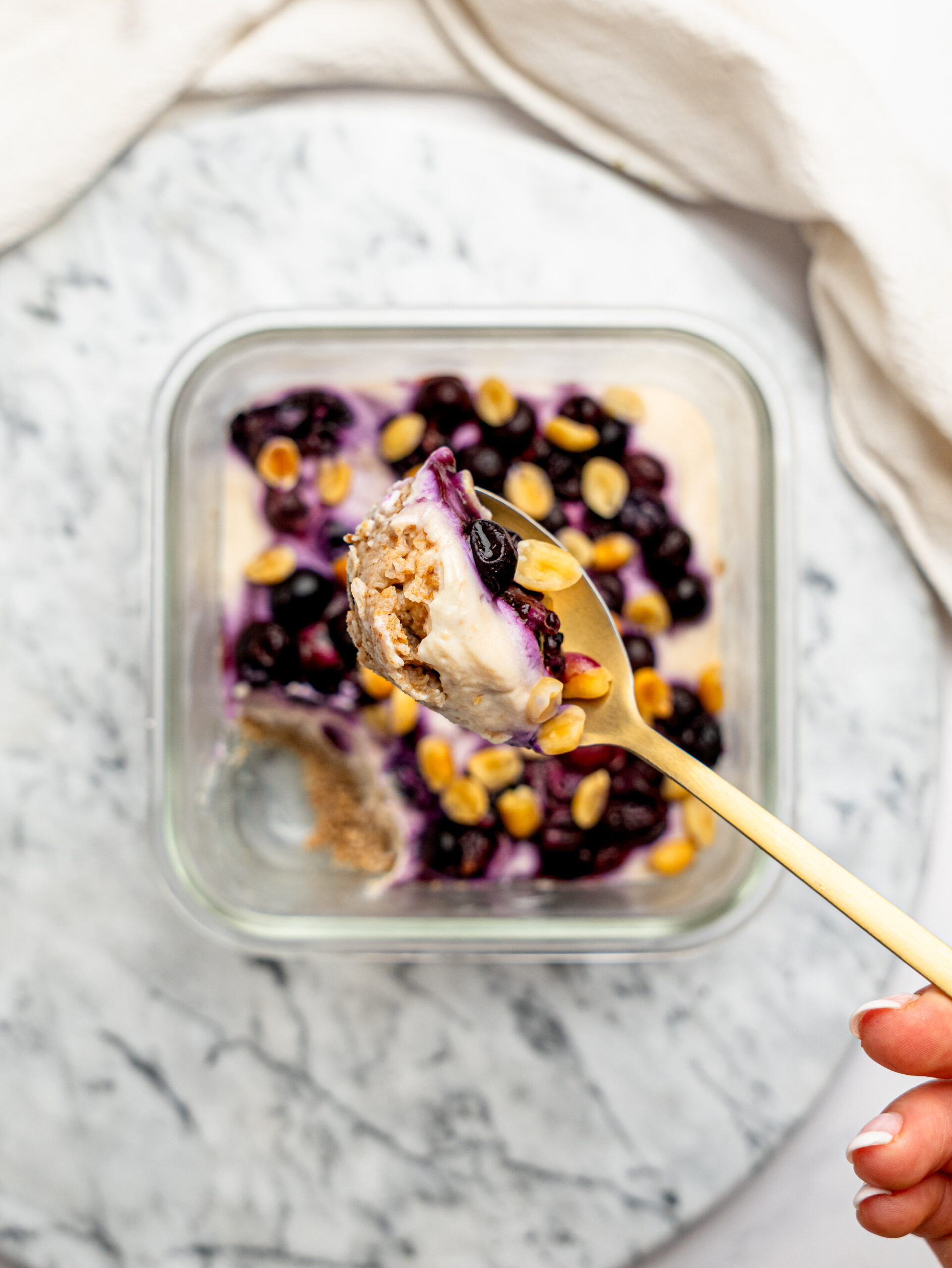 Close-up spoonful of PB&J Overnight Weetbix showing layers of softened Weetbix, peanut butter yogurt, berries, and peanuts.