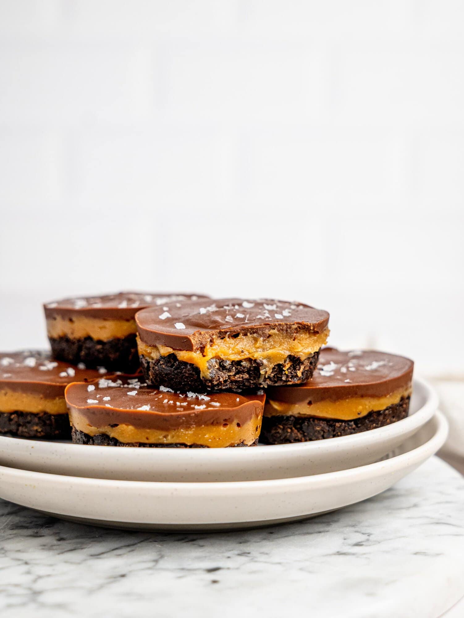 No-Bake Snickers Weetbix Cups displayed on a wooden serving board with smooth chocolate tops and creamy peanut butter layers.