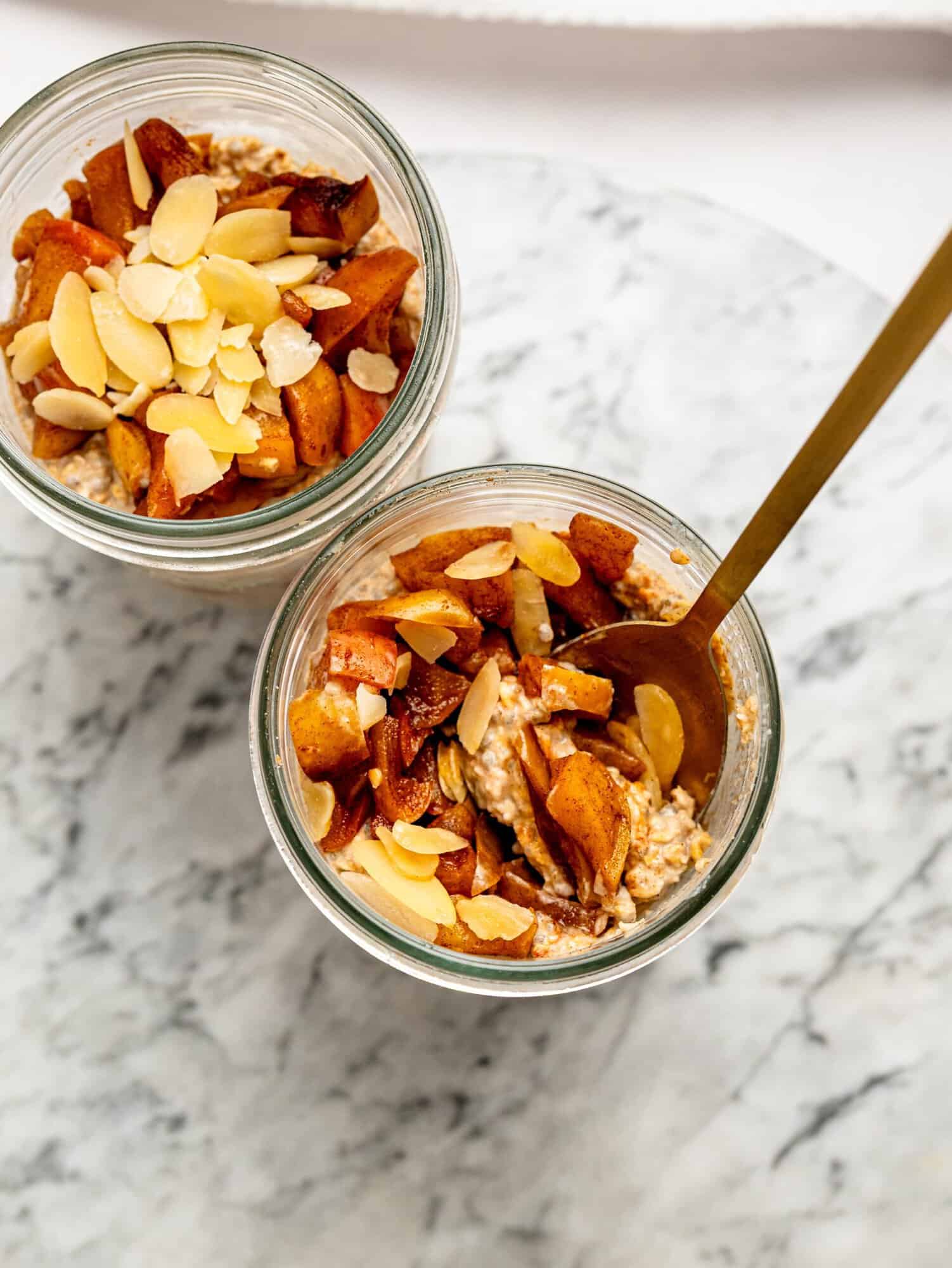 Apple Pie Overnight Oats topped with caramelized cinnamon apples and sliced almonds in glass jars.
