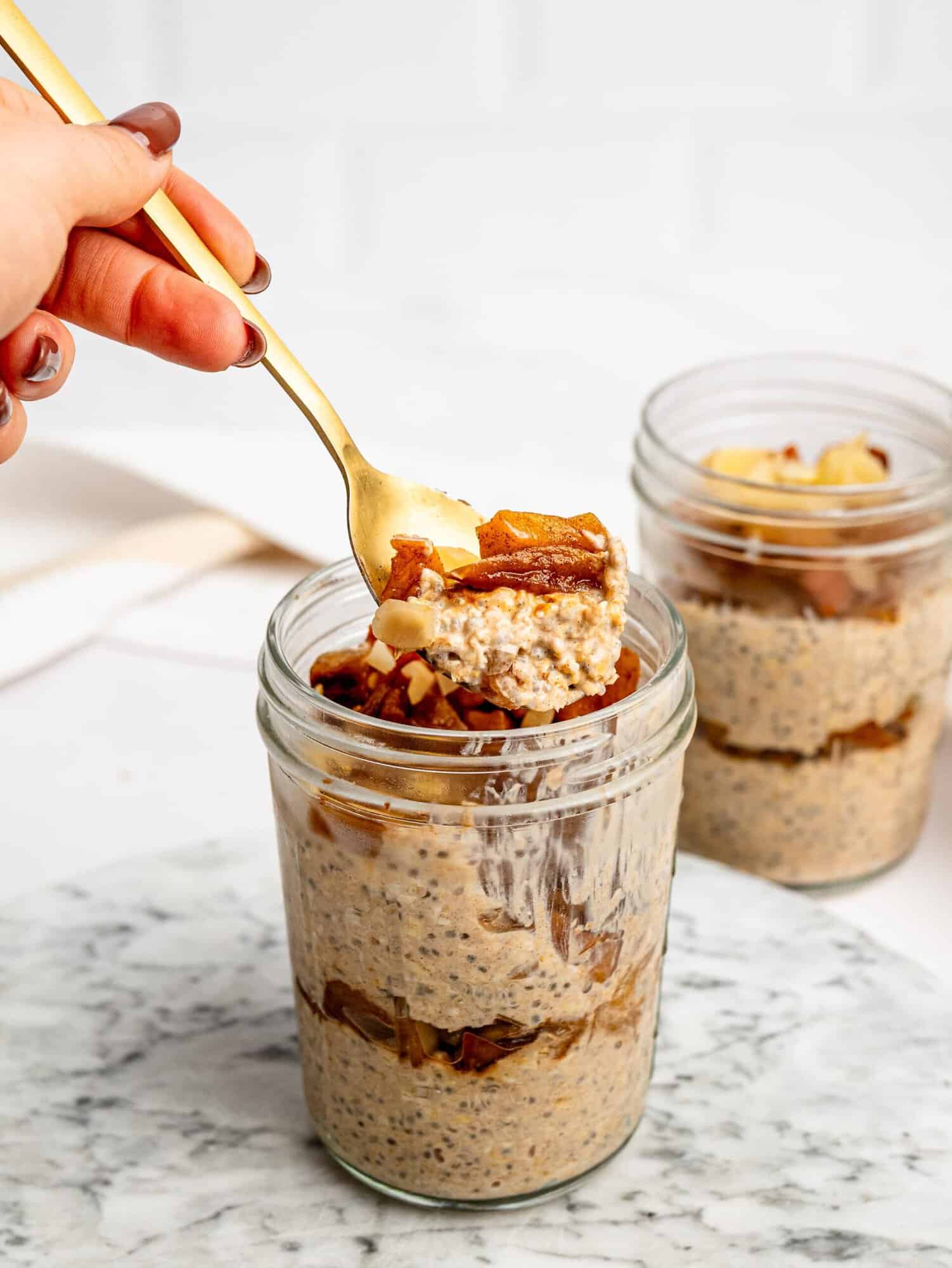 Spoonful of creamy Apple Pie Overnight Oats with caramelized apples and sliced almonds.
