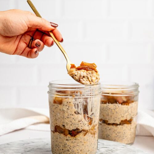 Close-up of layered Apple Pie Overnight Oats with cinnamon apples in a glass jar.