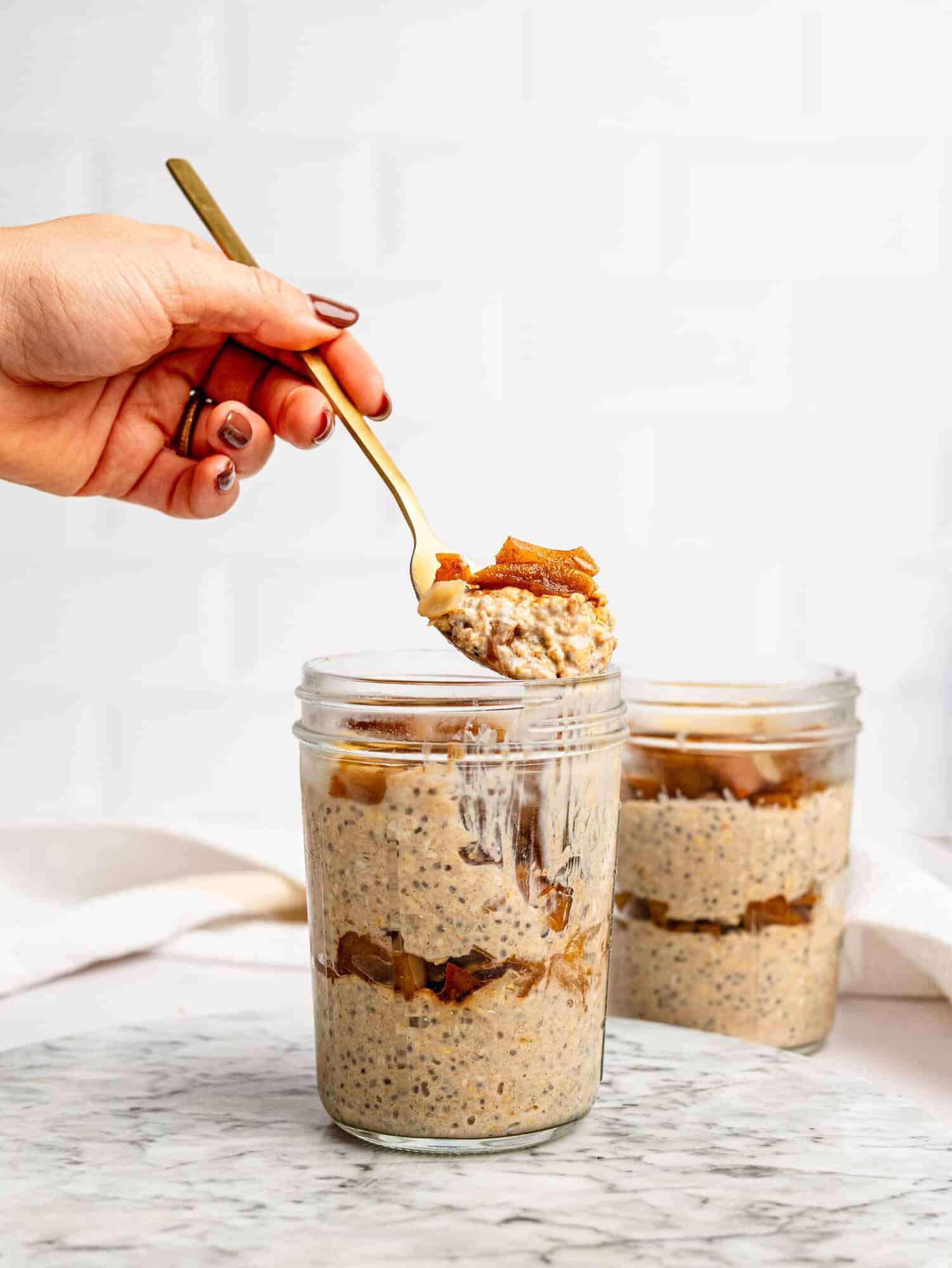Close-up of layered Apple Pie Overnight Oats with cinnamon apples in a glass jar.