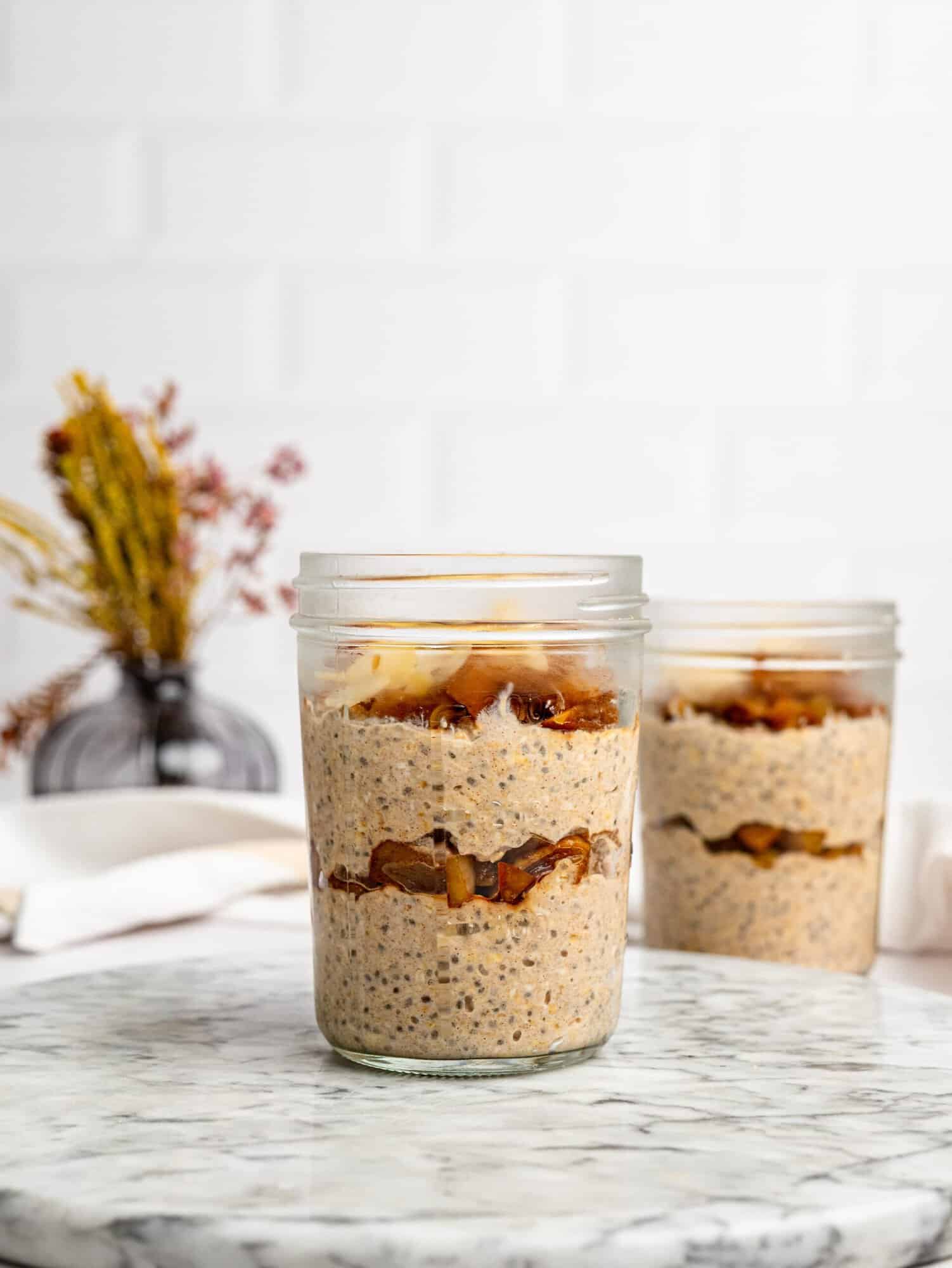 Apple Pie Overnight Oats in a glass jar with caramelized apples on top.