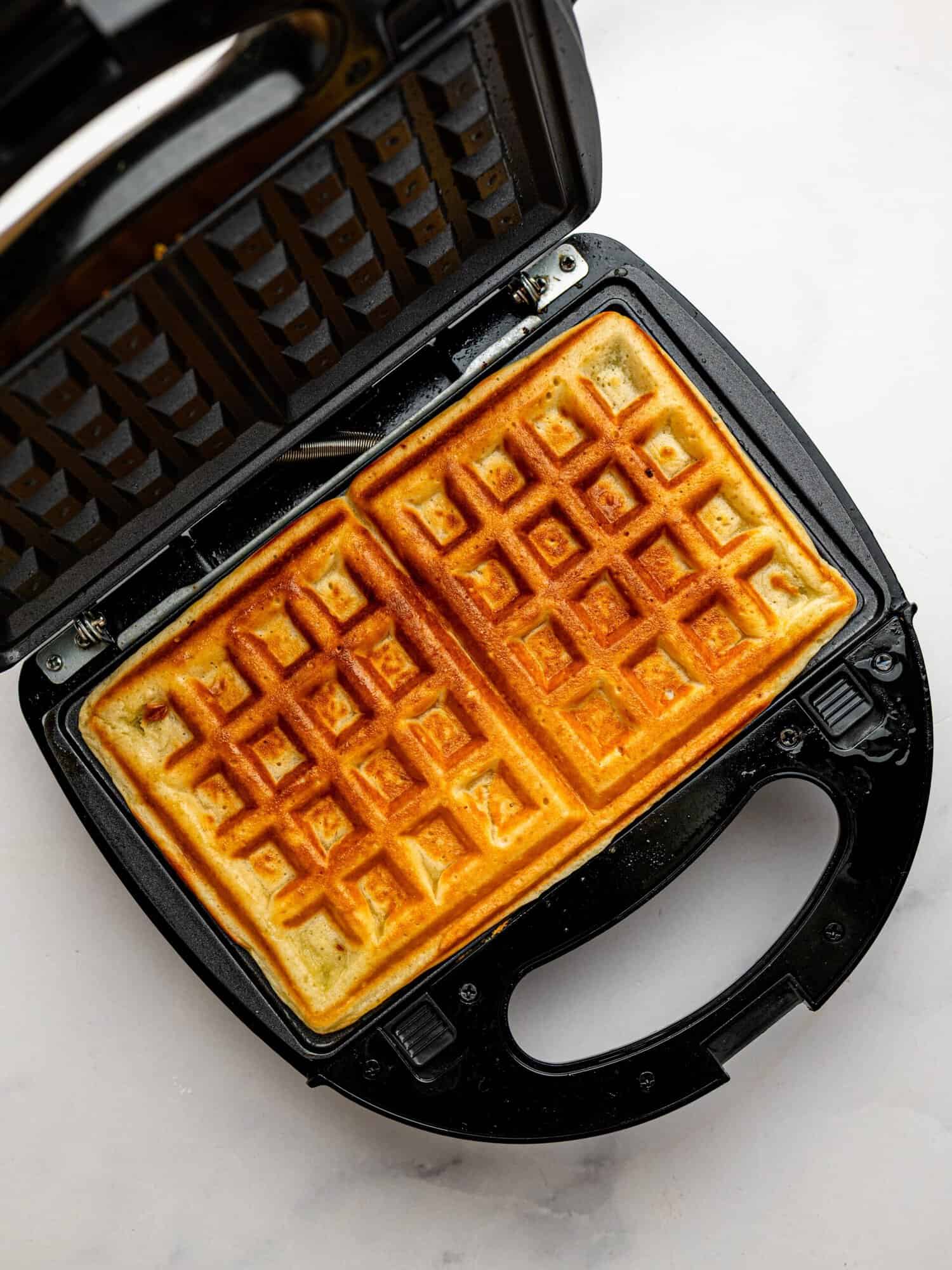 Golden gluten-free waffles cooking in a waffle maker until crispy and fluffy.