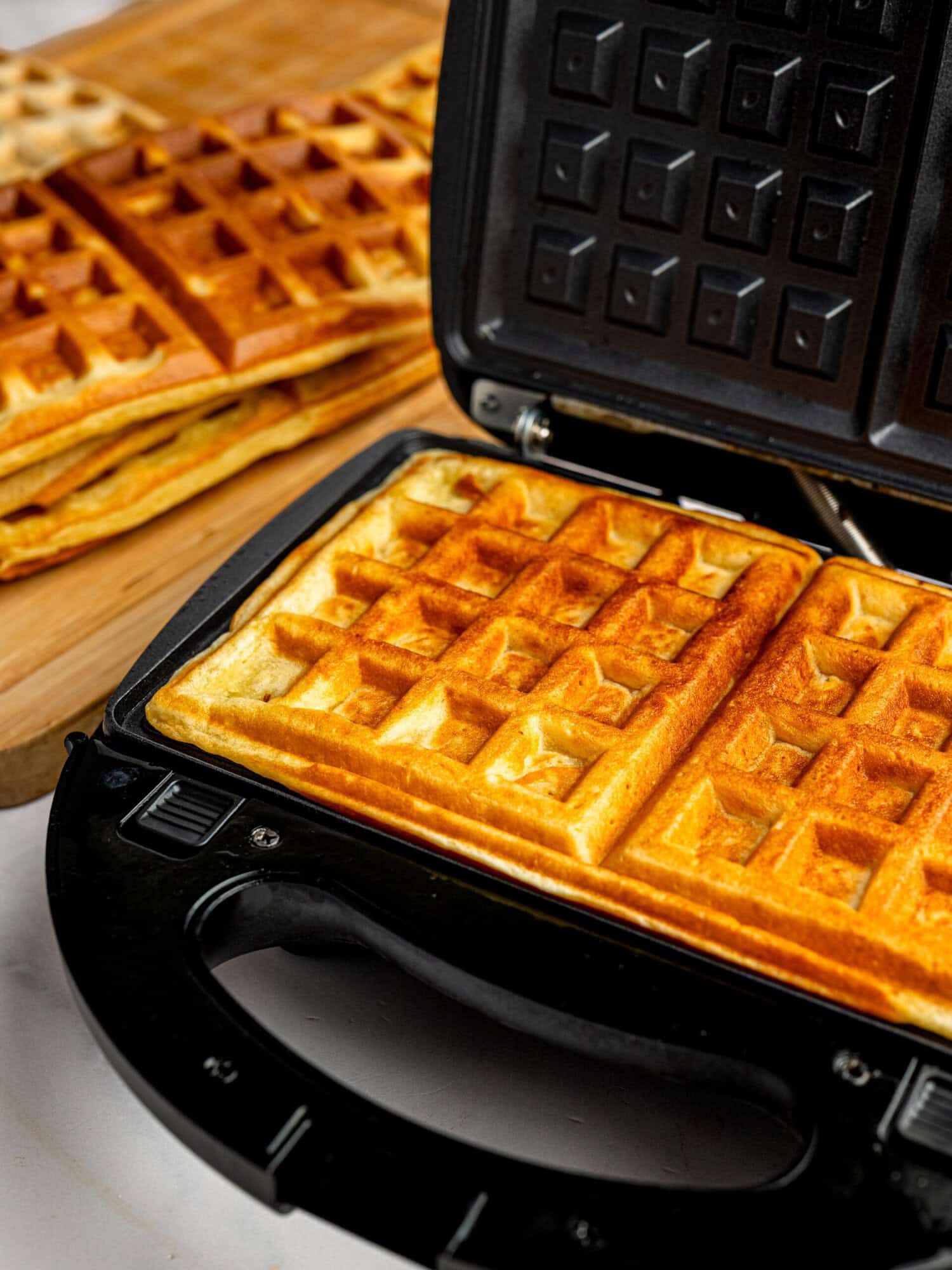 Cooking homemade gluten-free waffles in a waffle maker until golden and crispy.