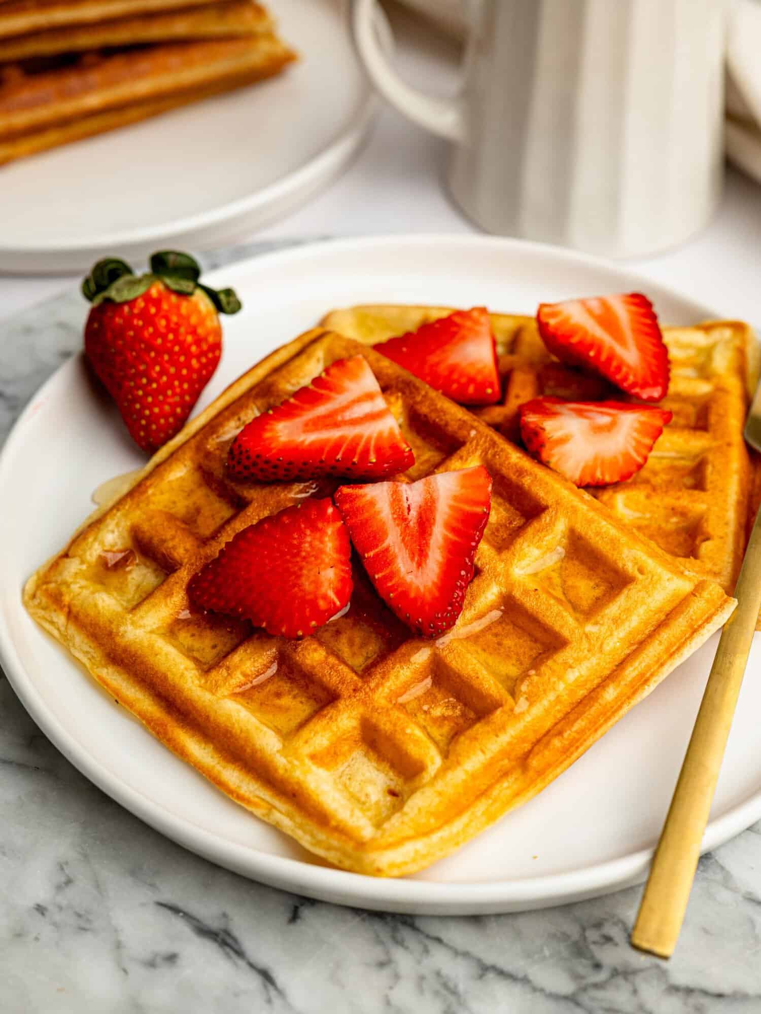 The Best Gluten Free Waffle Recipe served with fresh strawberries and honey.