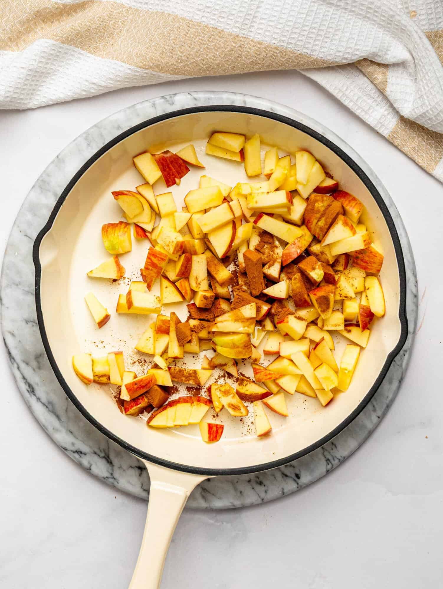 Diced apples and cinnamon in a skillet before cooking into caramelized apples.
